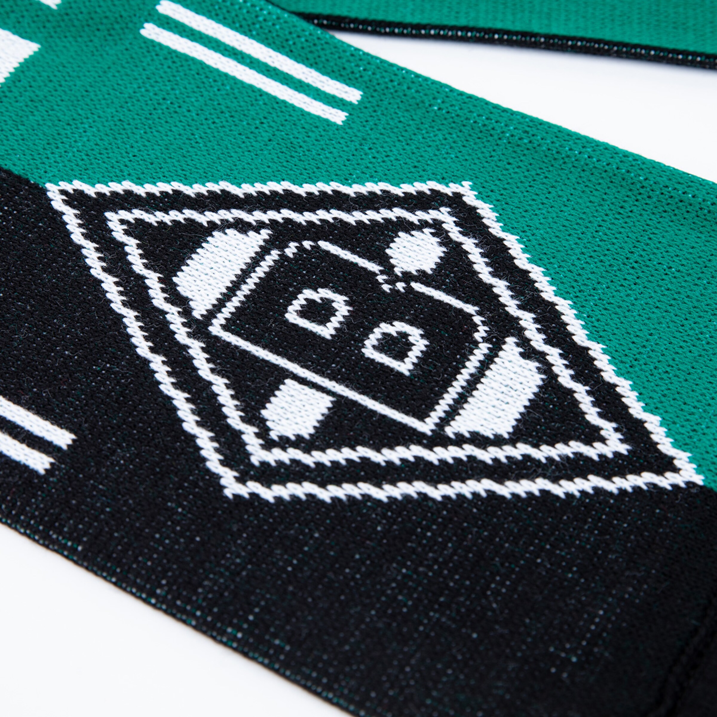 Nahaufnahme eines grün-schwarzen Strickschals mit dem Rauten-Logo von Borussia Mönchengladbach und weißen Streifen.