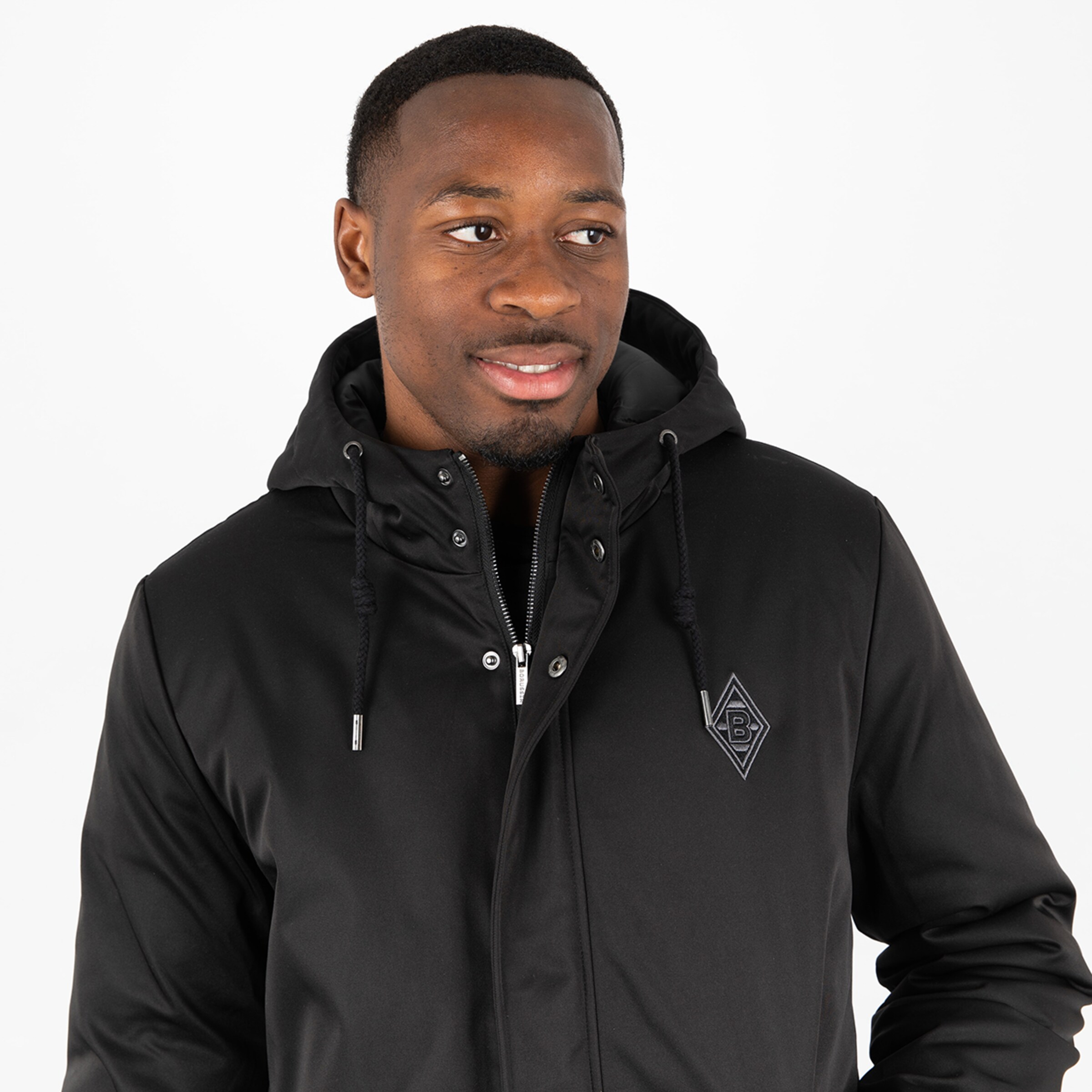 Mann in schwarzer Jacke mit Kapuze und Logo von Borussia Mönchengladbach.