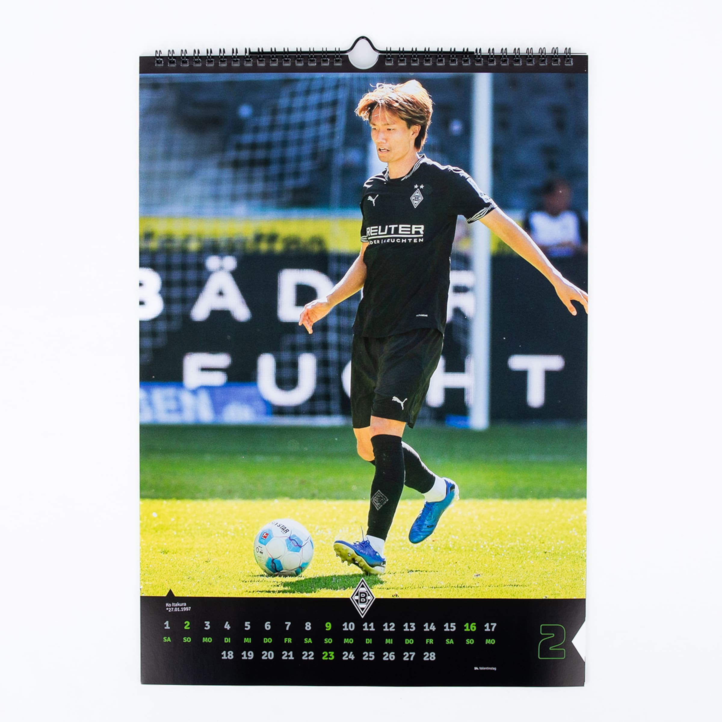 Fußballspieler in schwarzem Trikot und Shorts auf Spielfeld mit Ball Kalenderblatt.