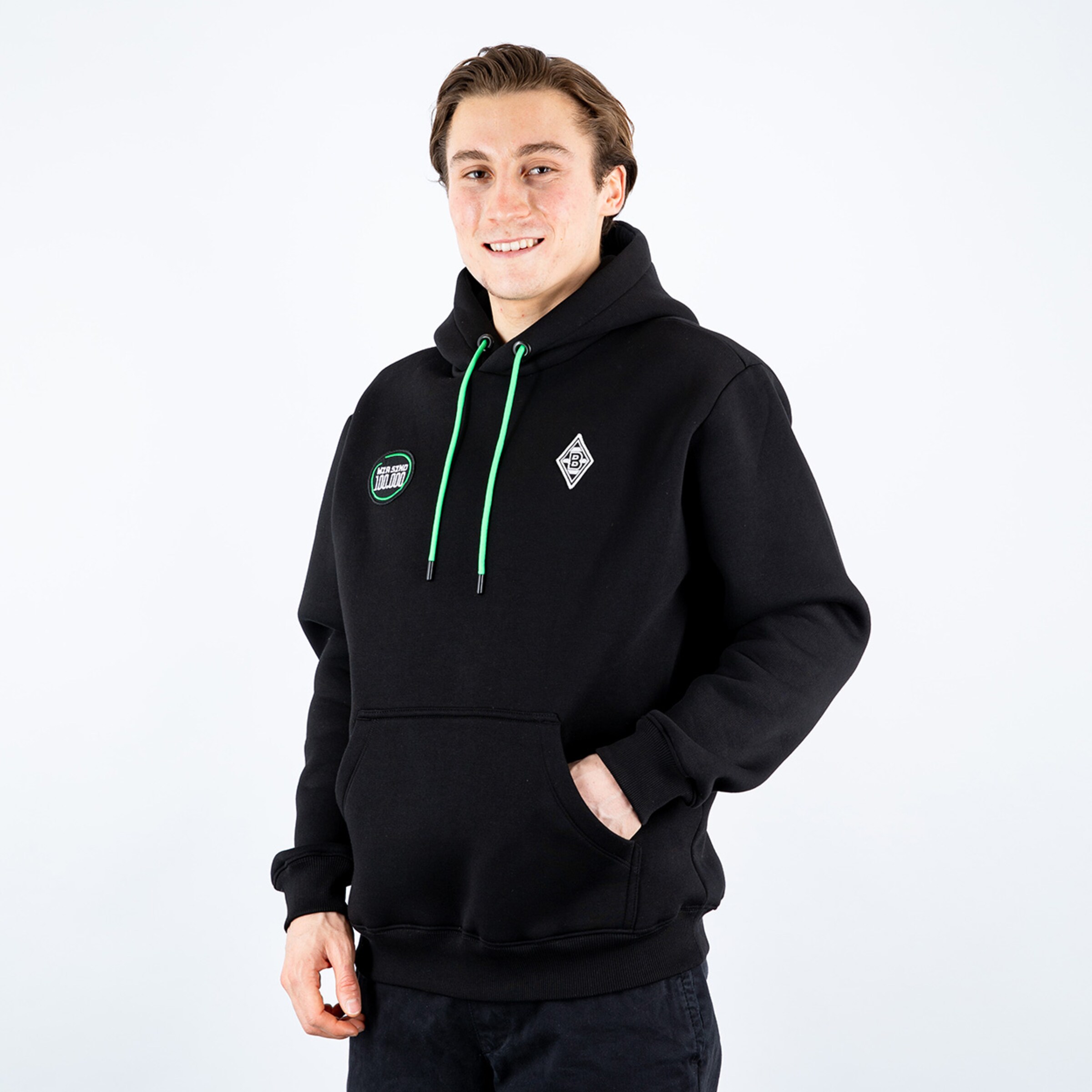 Mann in schwarzem Kapuzenpullover mit grünem Kordelzug und Borussia Mönchengladbach-Logos.