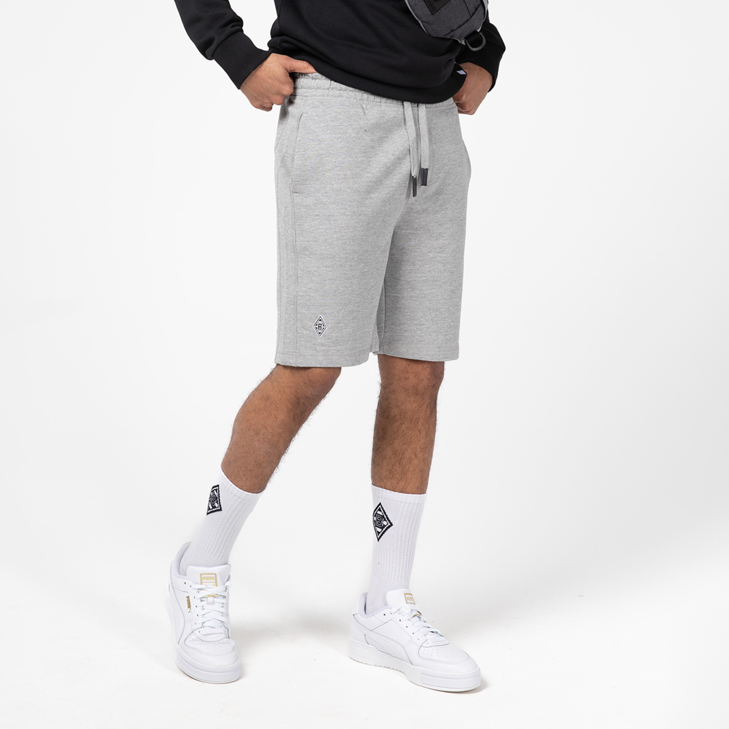 Mann trägt graue Shorts mit weißen Sneakers und weißen Socken