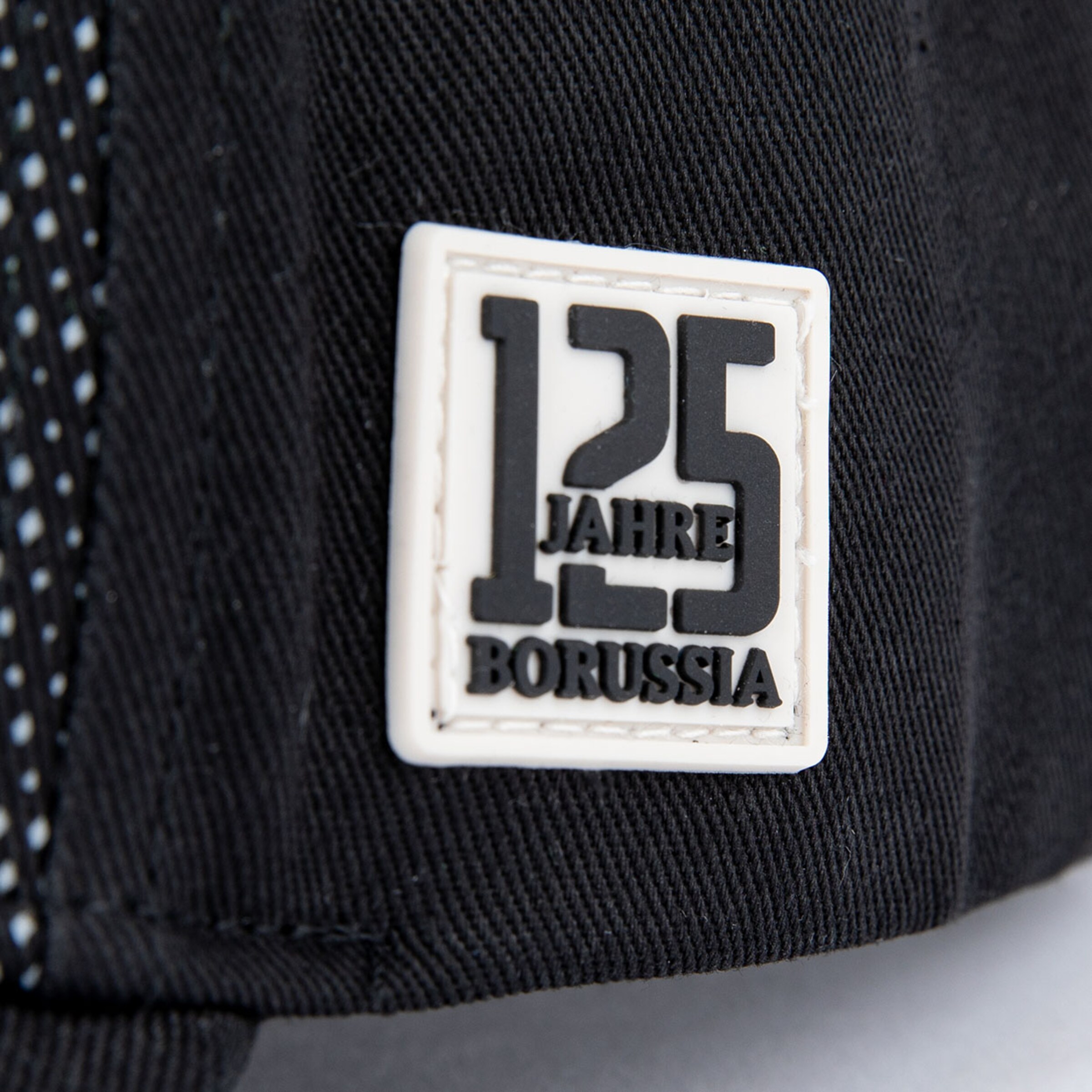 Logo mit 125 Jahre Borussia auf einem schwarzen Stoff rechteckig in weißer Schrift.