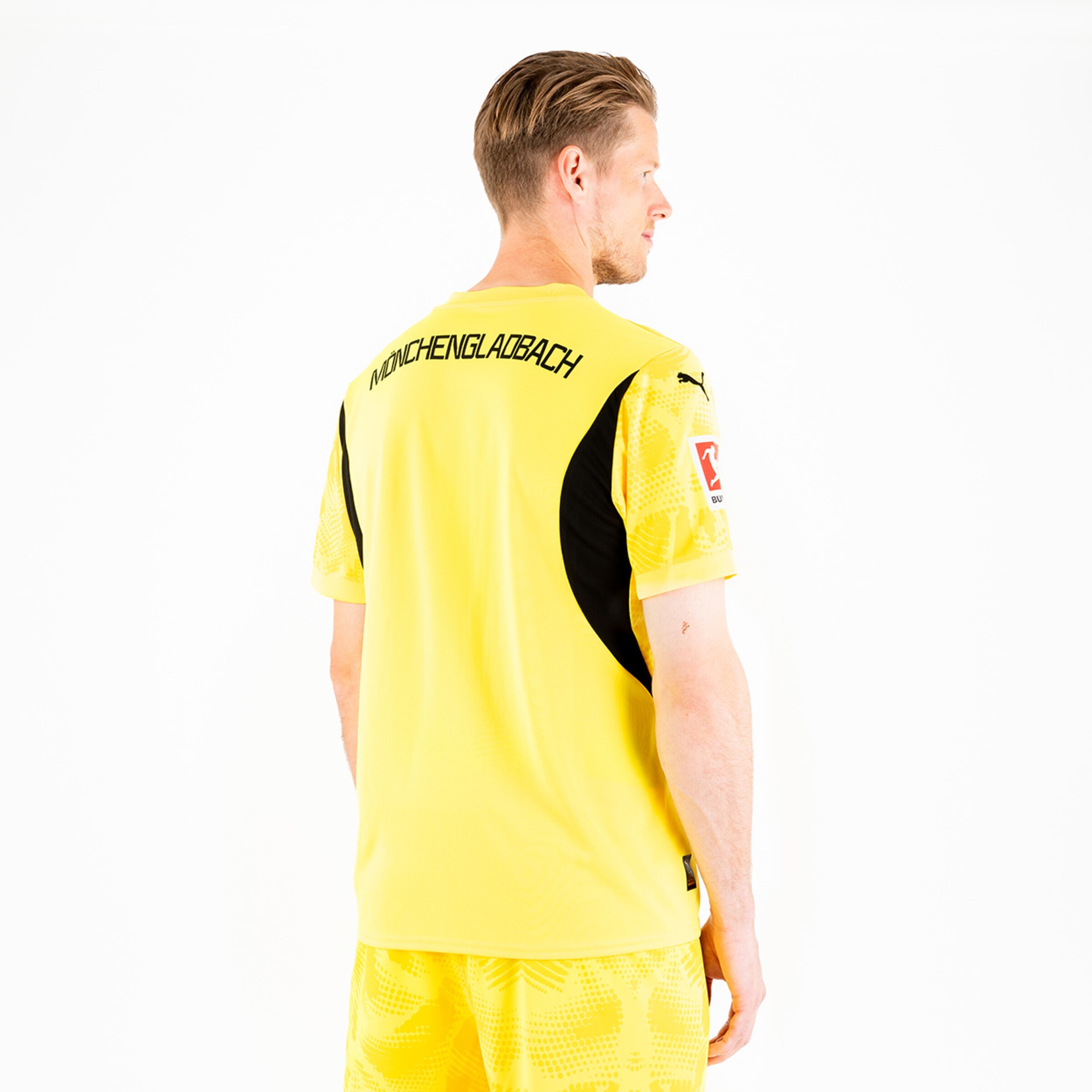 Spieler trägt gelbes Trikot mit dem Schriftzug MÖNCHENGLADBACH auf dem Rücken.