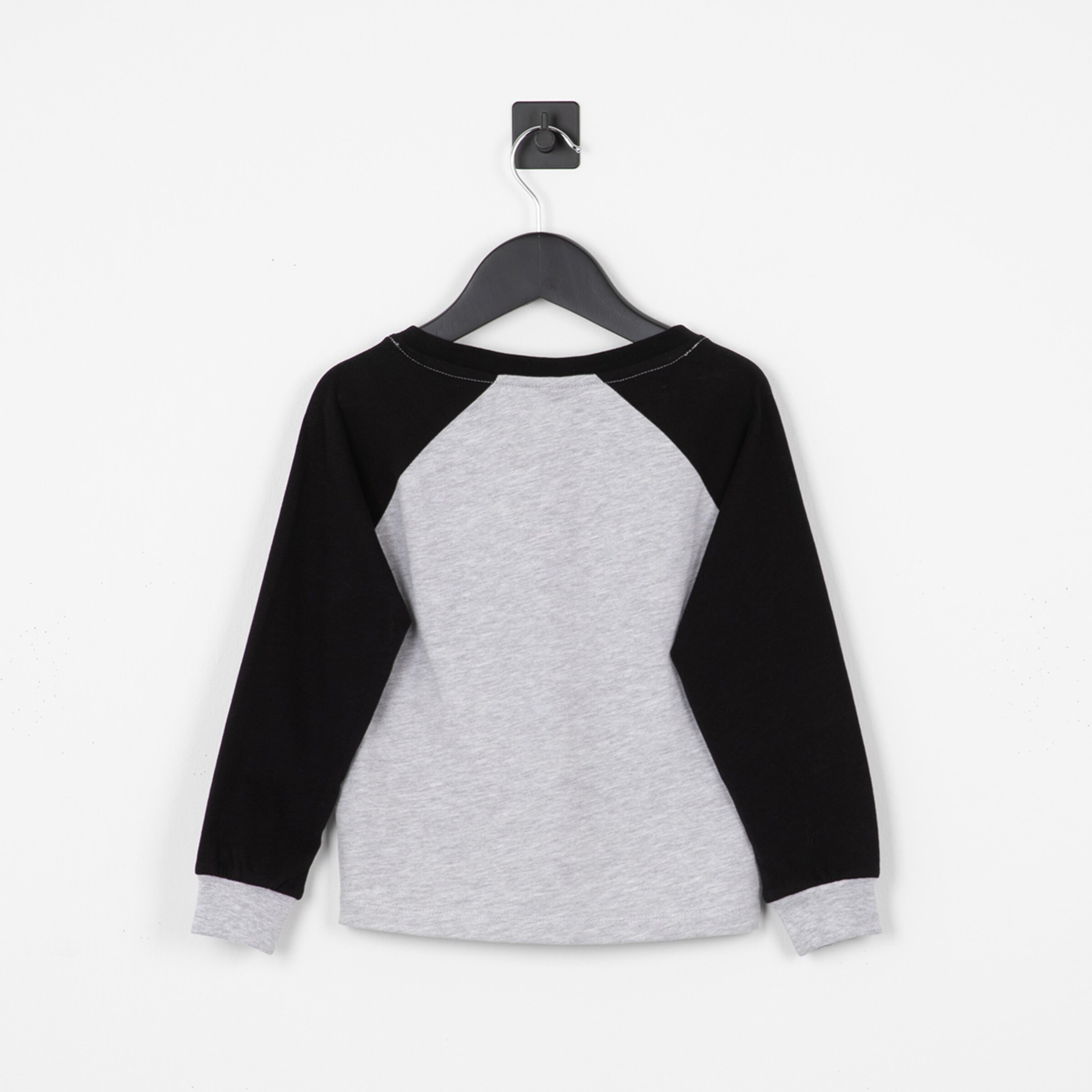 Langarmshirt mit grauer Vorderseite und schwarzen Ärmeln aufgehangt an einem Haken.