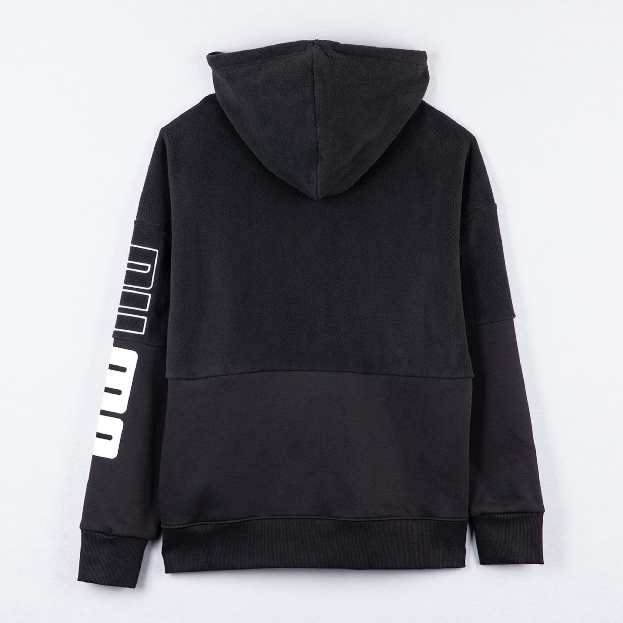 Schwarzer Hoodie in der Rückansicht, Materialmix aus Fleece oben und glattem Stoff unten, weißer Schriftzug am linken Ärmel.