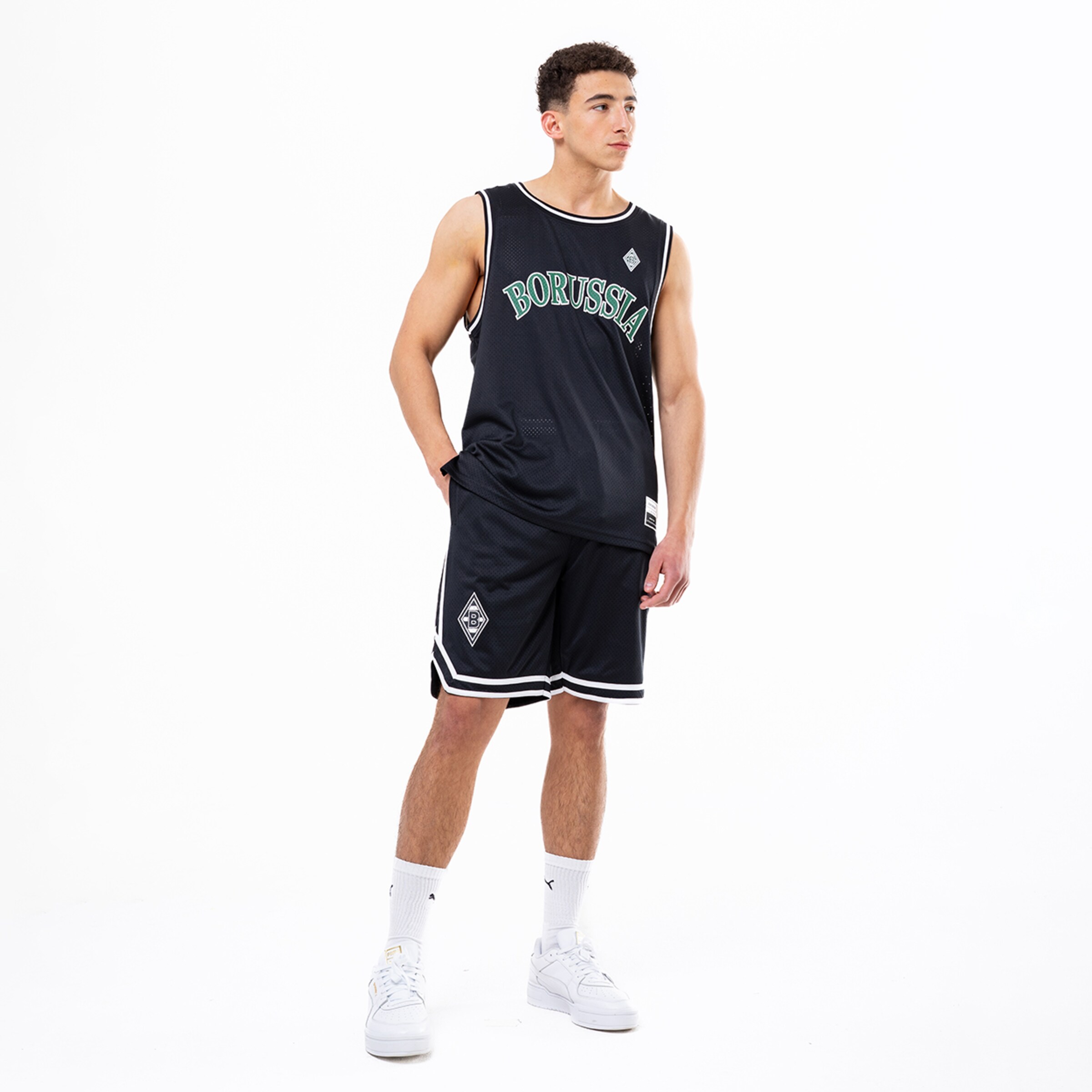 Mann in schwarzem Basketballtrikot und Shorts von Borussia Mönchengladbach mit Logo und sportlichen Sneakers.