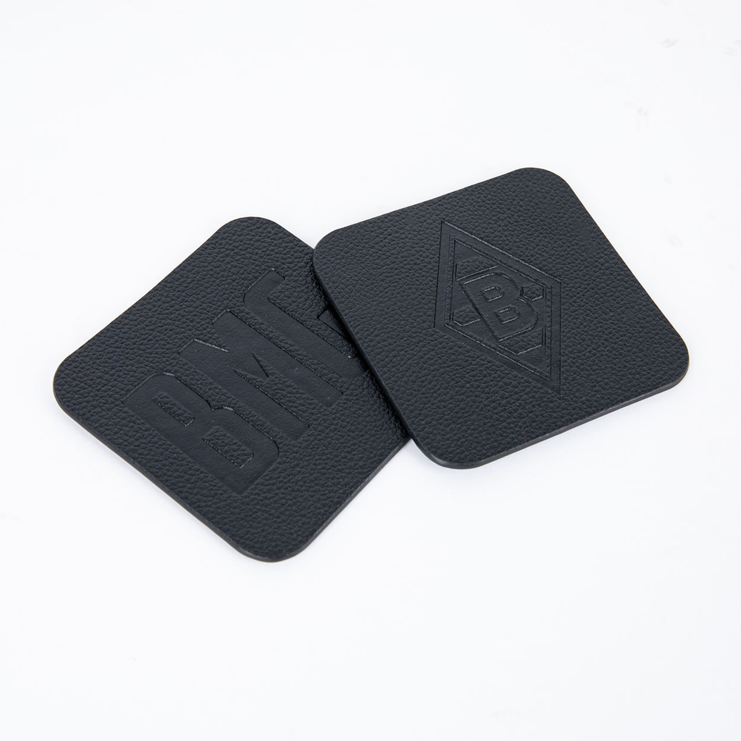 Two black coasters featuring an embossed BMG logo on one side.
