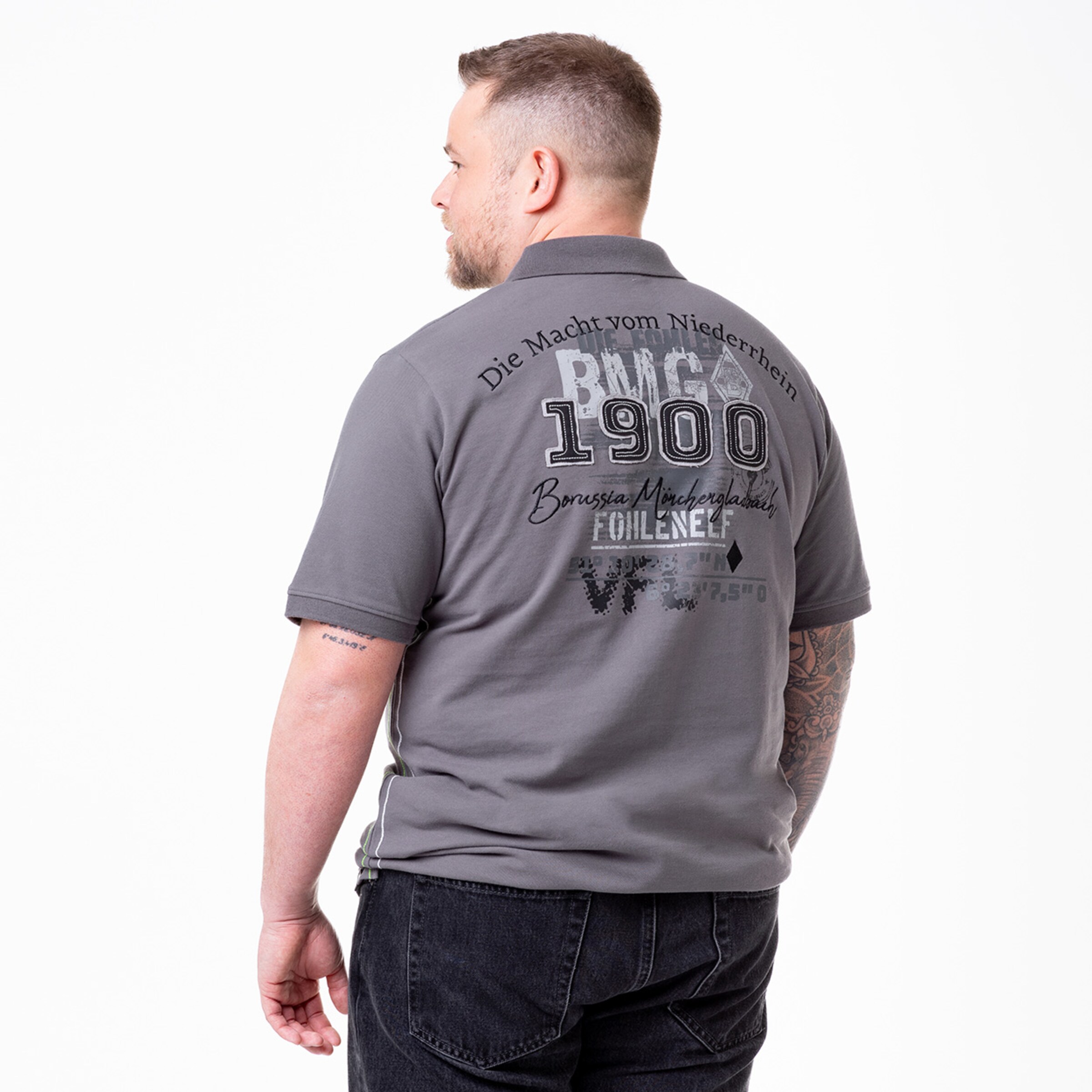 Rückansicht eines Mannes in einem grauen Poloshirt mit Aufdruck Die Macht vom Niederrhein 1900 Borussia Mönchengladbach.