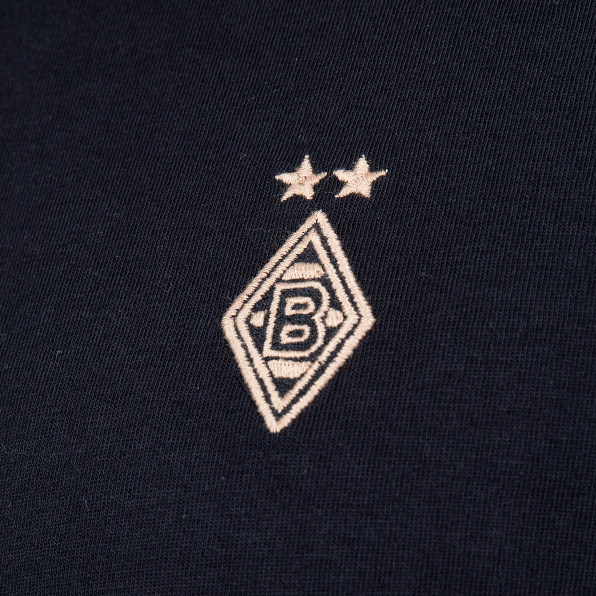 Gesticktes Borussia Mönchengladbach Logo auf dunklem Stoff: Beige Raute mit schwarzem B und zwei darüberliegenden Sternen.