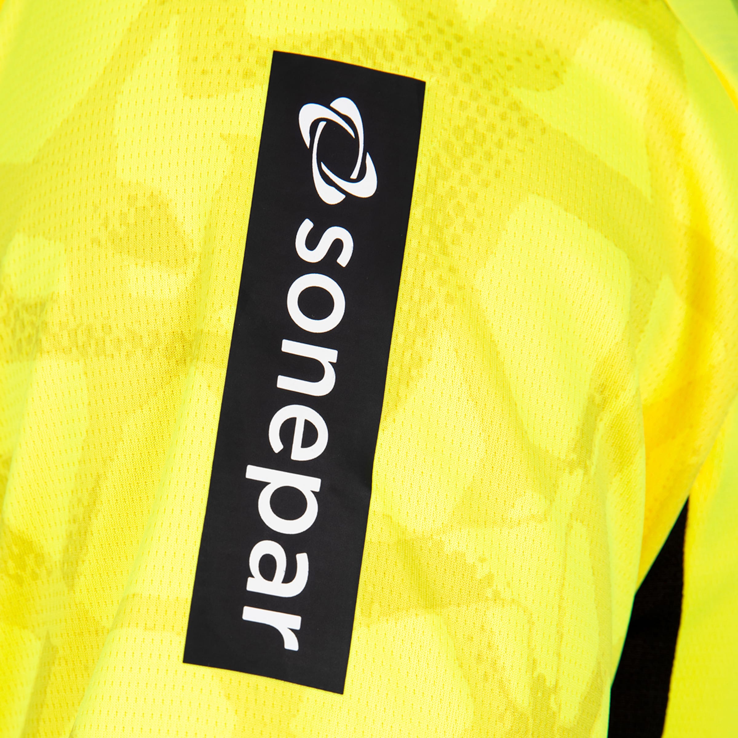 Nahaufnahme eines neongelben Trikotärmels mit einem vertikalen schwarzen Sponsoren-Patch, der das weiße Sonepar-Logo zeigt.