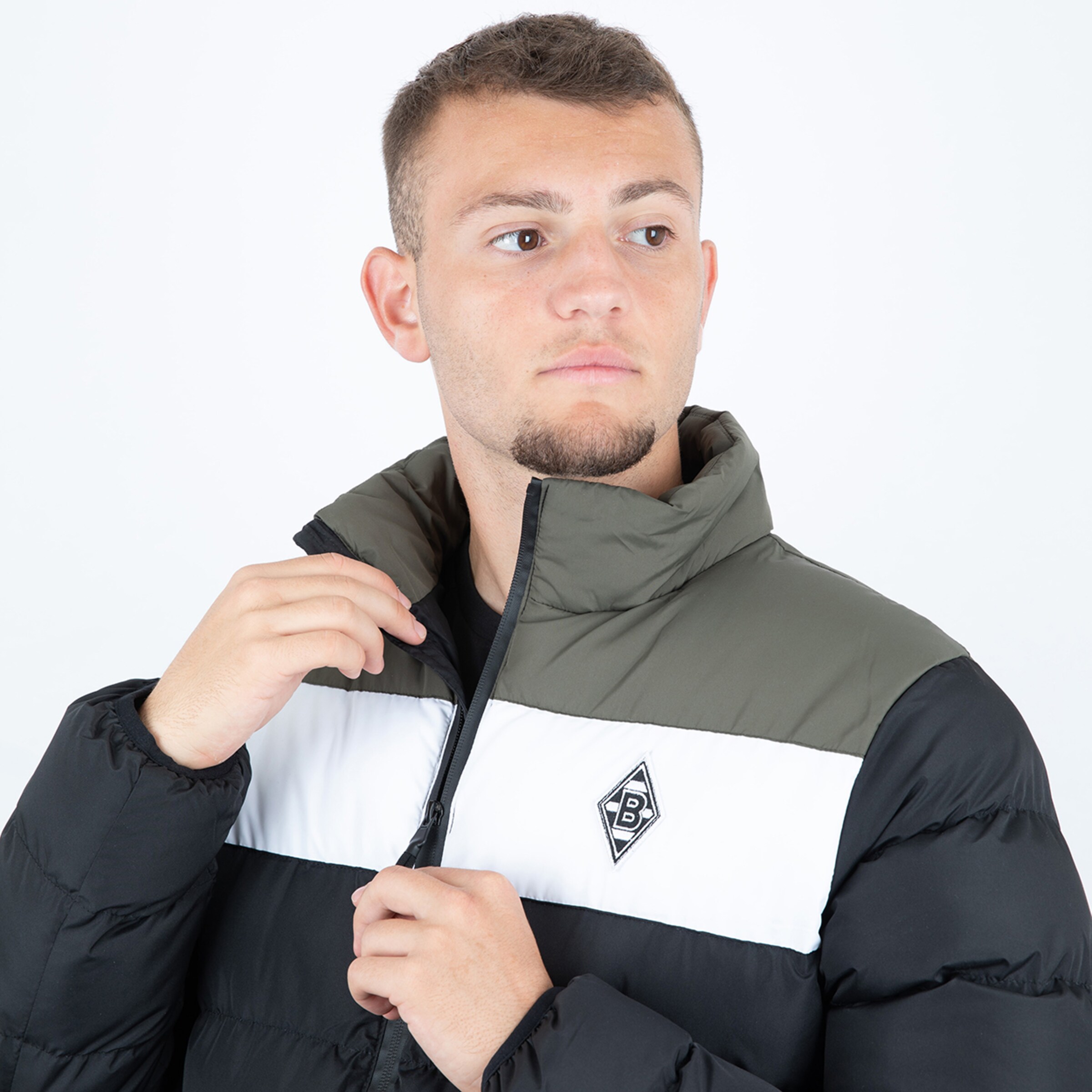 Junger Mann trägt eine schwarze und graue Jacke mit Borussia Mönchengladbach-Logo.