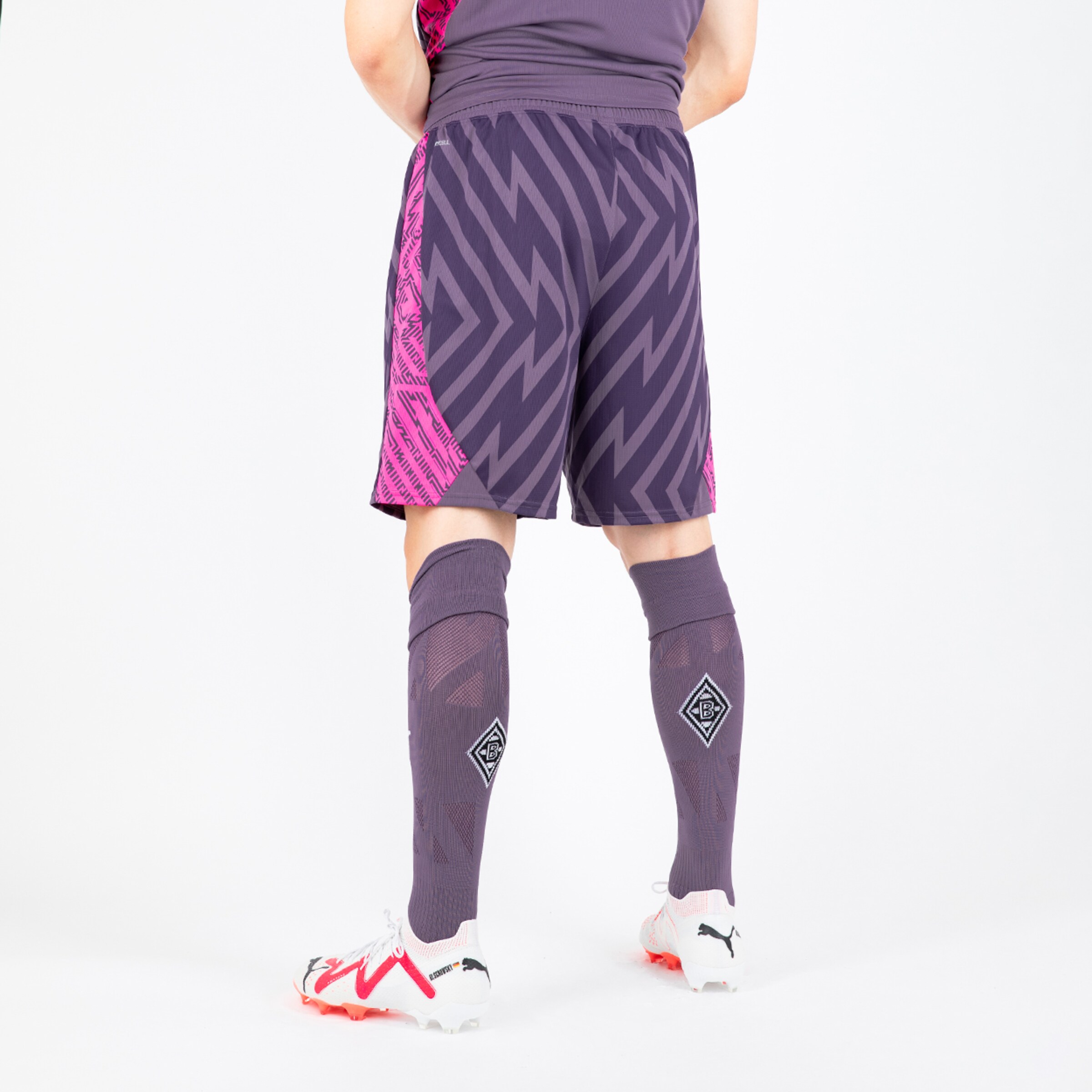 Ein Spieler von Borussia Mönchengladbach von hinten trägt lila Fußballshorts und Socken mit Logo.