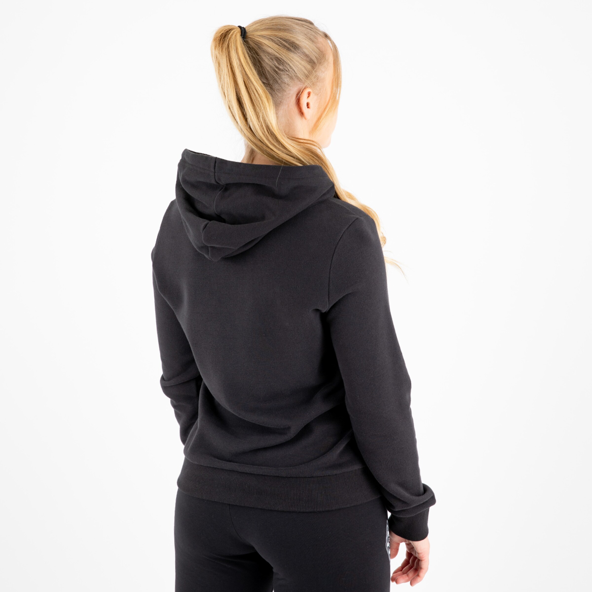 Dame in schwarzem Hoodie von hinten mit langer blonder Haarfrisur und entspanntem Ausdruck.