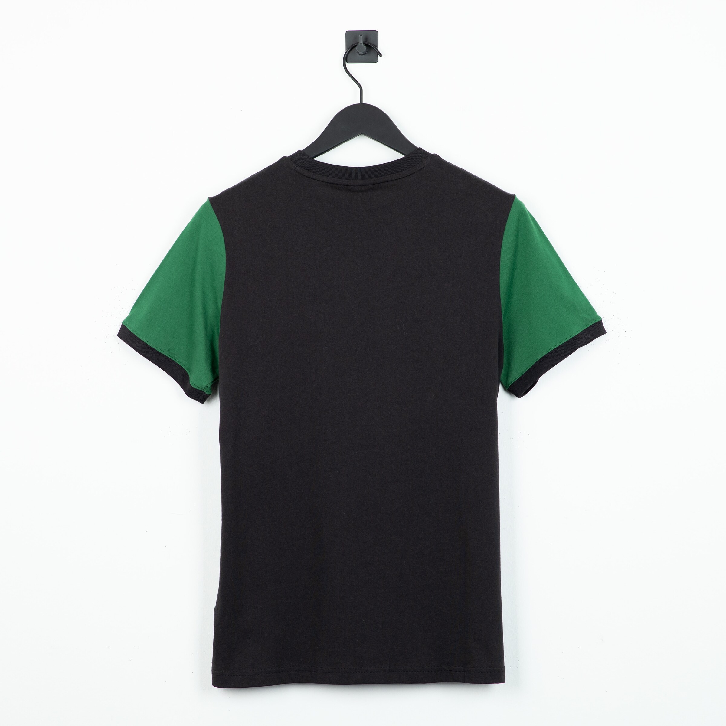 Black t-shirt with green sleeves hanging from a clothes hanger viewed from the back.