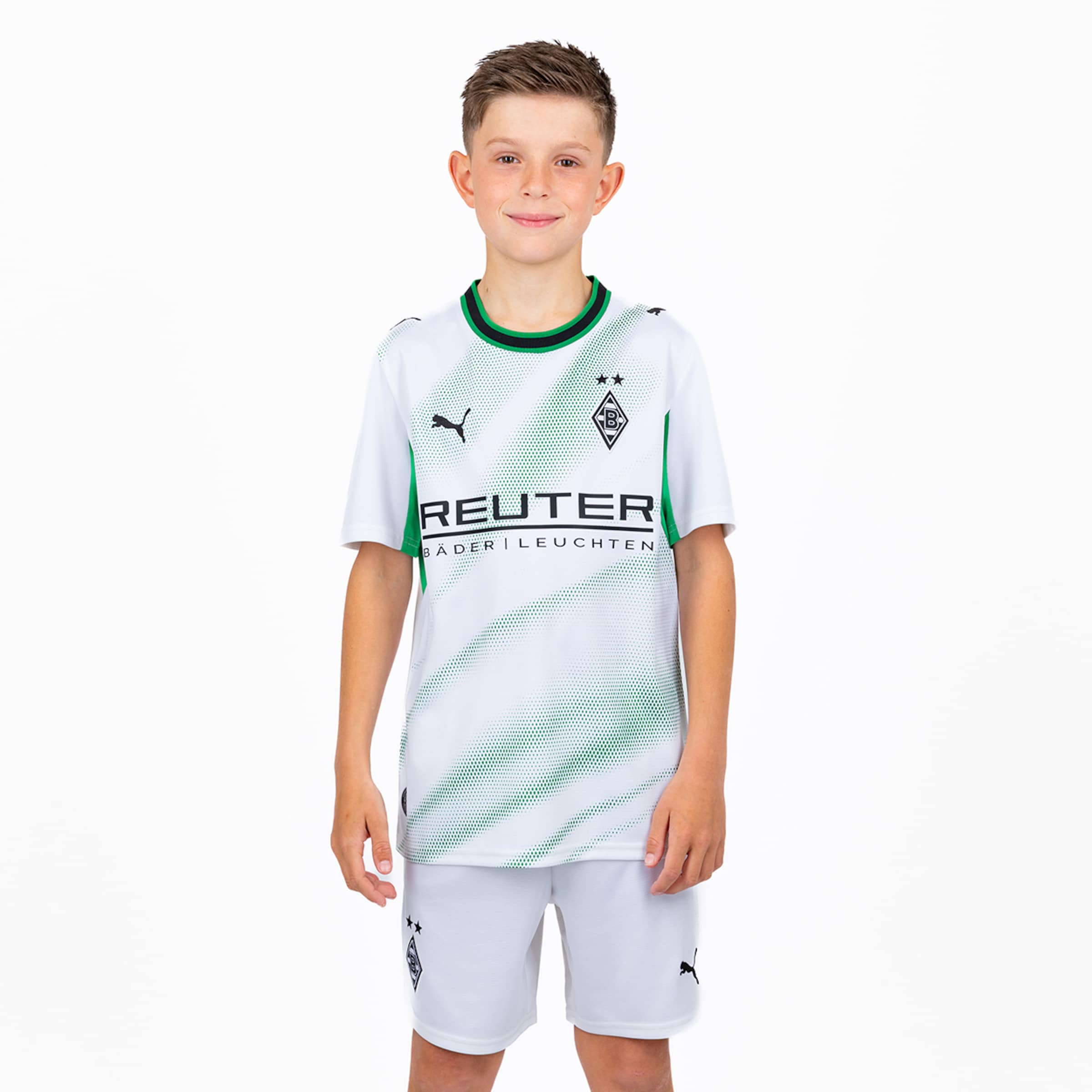 Junge im weißen Borussia Mönchengladbach Trikot mit grünen Akzenten, Puma-Logo und Reuter-Sponsor vor weißem Hintergrund.