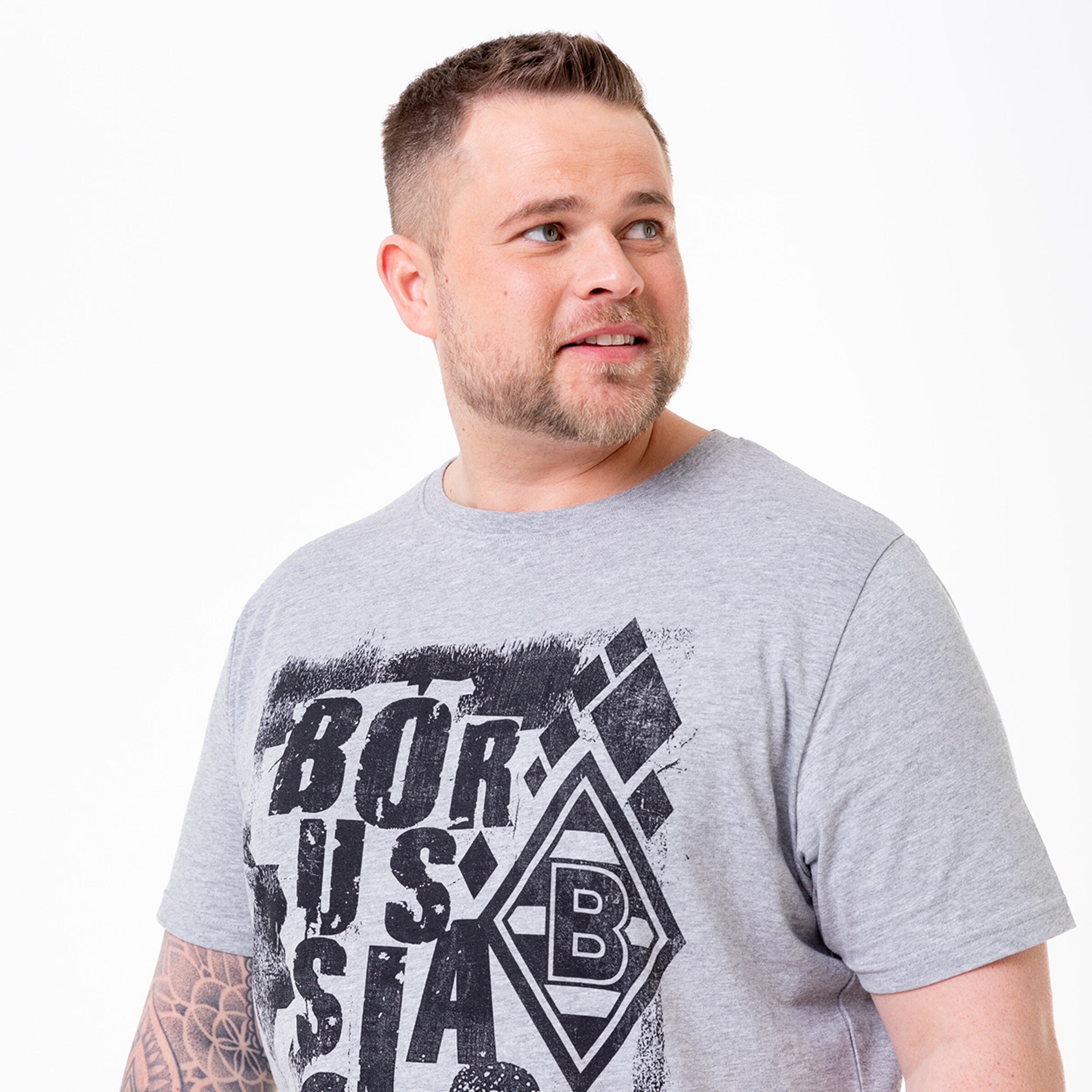 Mann mit kurzen Haaren und Bart in grauem T-Shirt mit Borussia Mönchengladbach-Logo.
