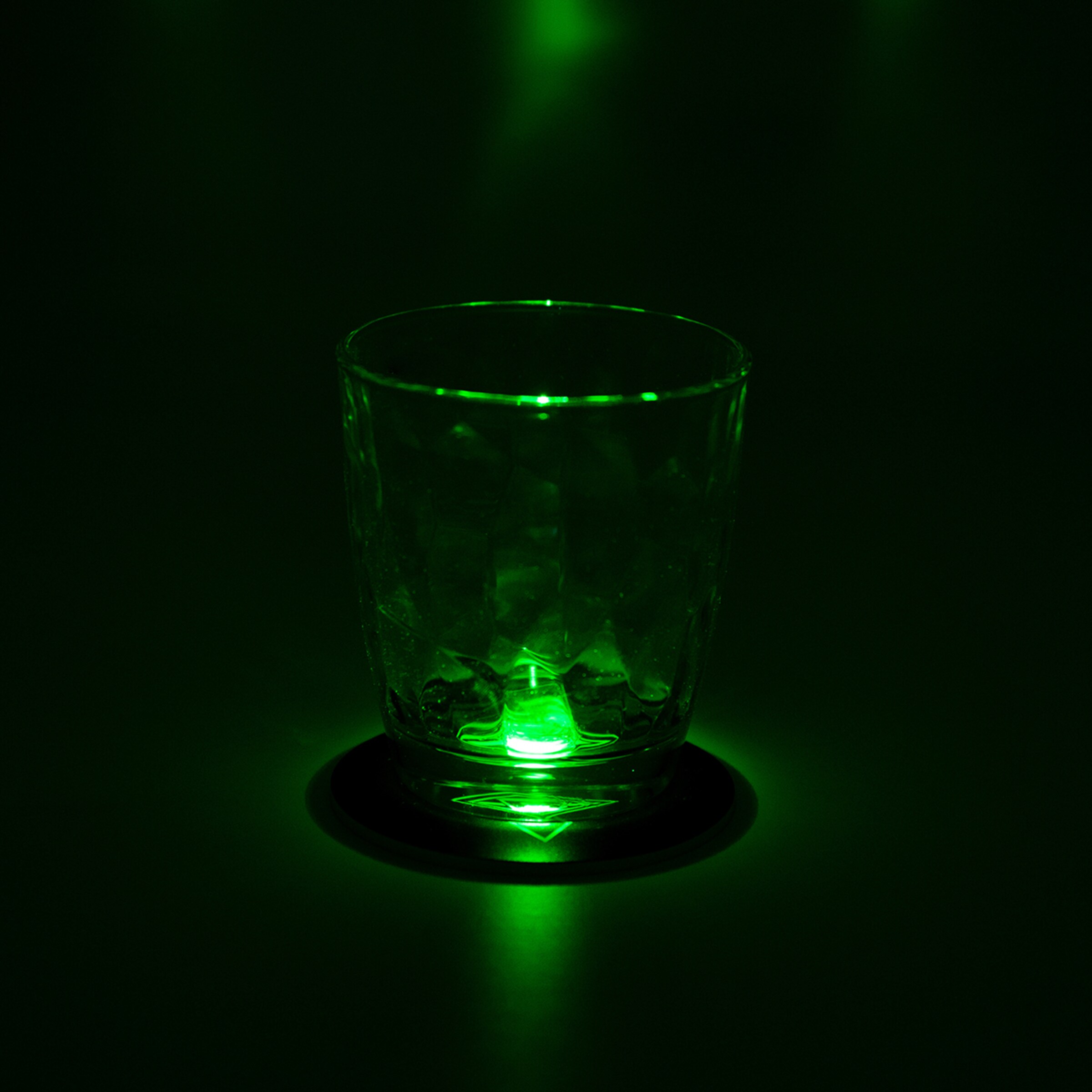 Ein gläserner Becher mit grünem Licht darunter das den Becher hervorhebt.