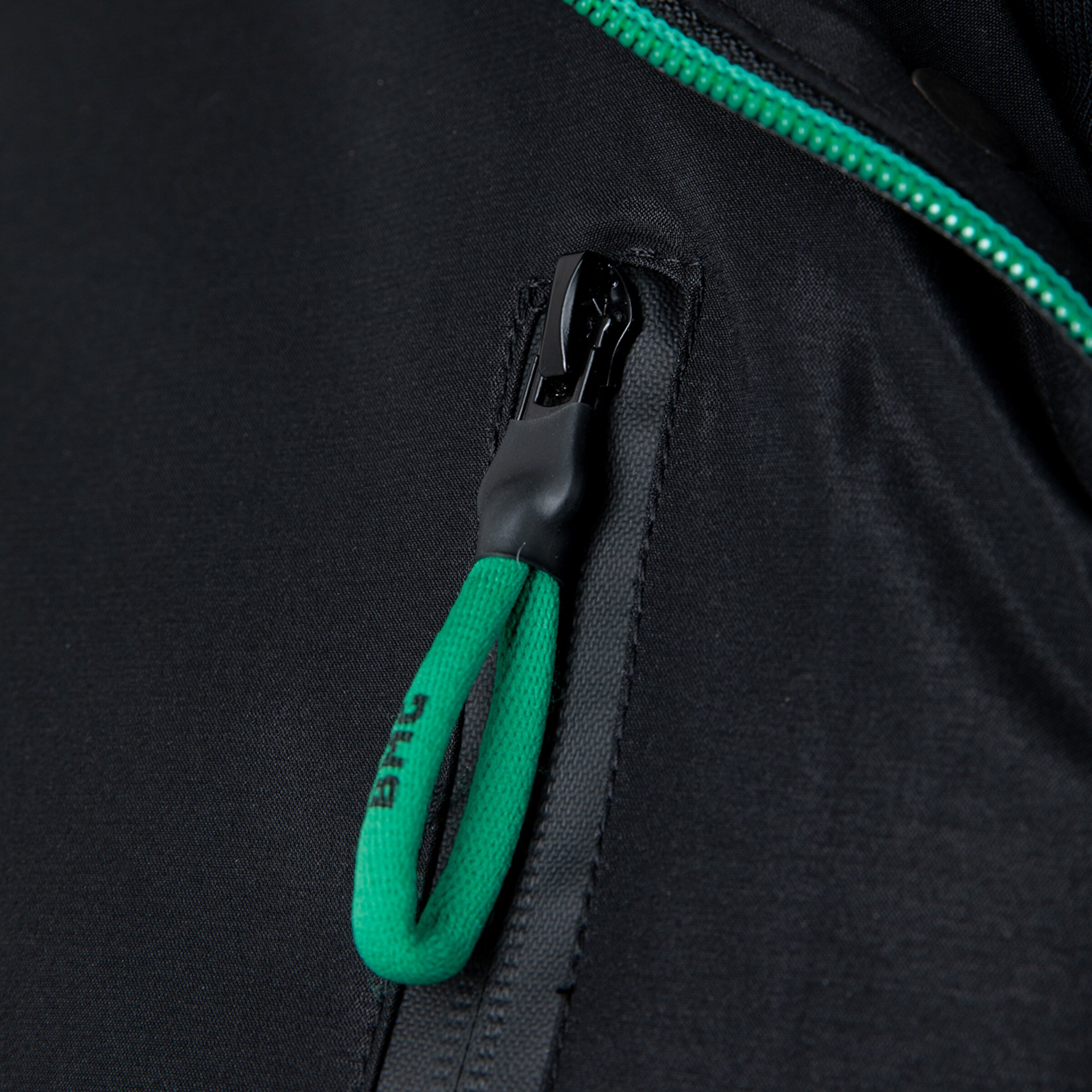 Details des Reißverschlusses einer schwarzen Jacke mit grünem Zipper.