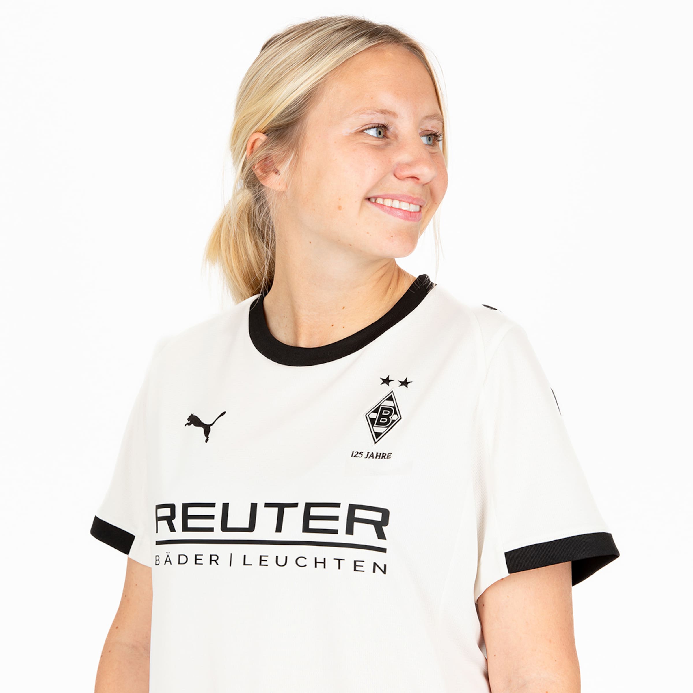 Eine Frau trägt ein weißes Borussia Mönchengladbach Trikot mit schwarzem Kragen und Sponsorenlogo.
