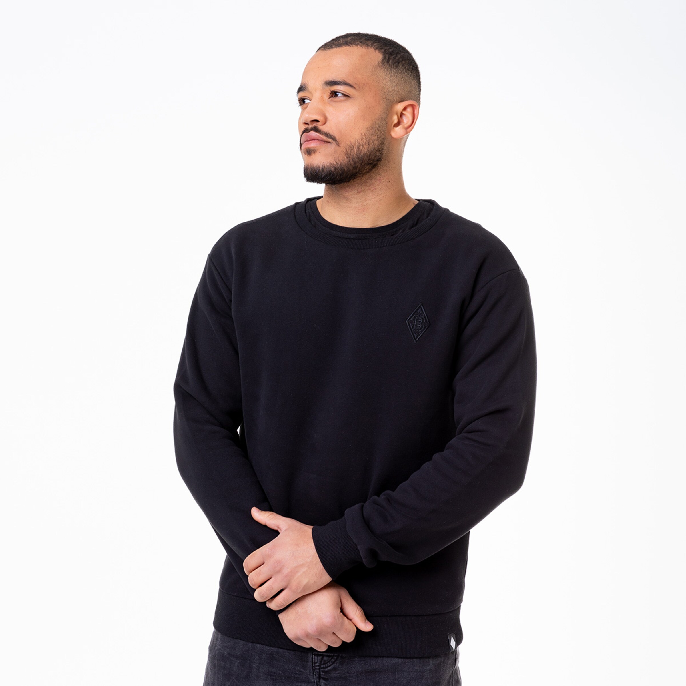 Man wearing a black sweatshirt with embroidered logo.