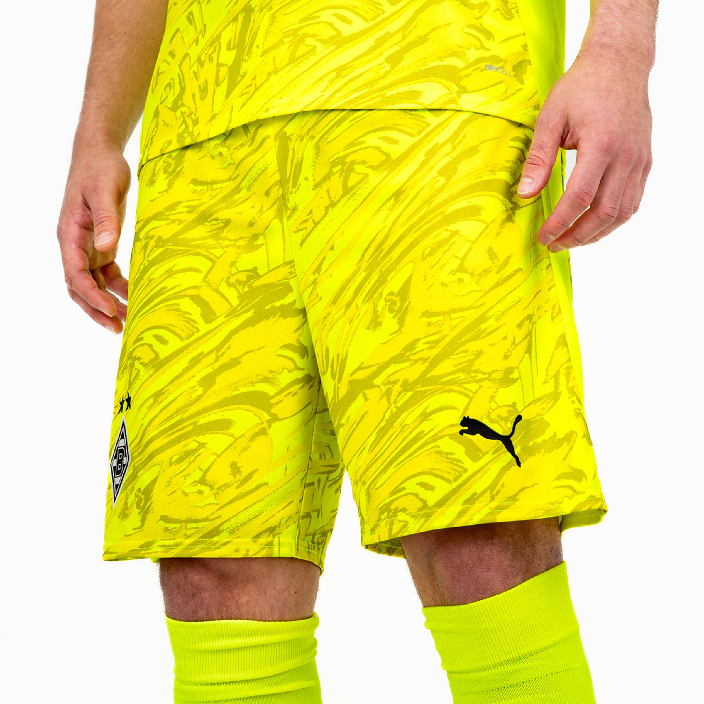 Neon colored soccer shorts with an abstract pattern and Puma logo. Upper body of a person shown.