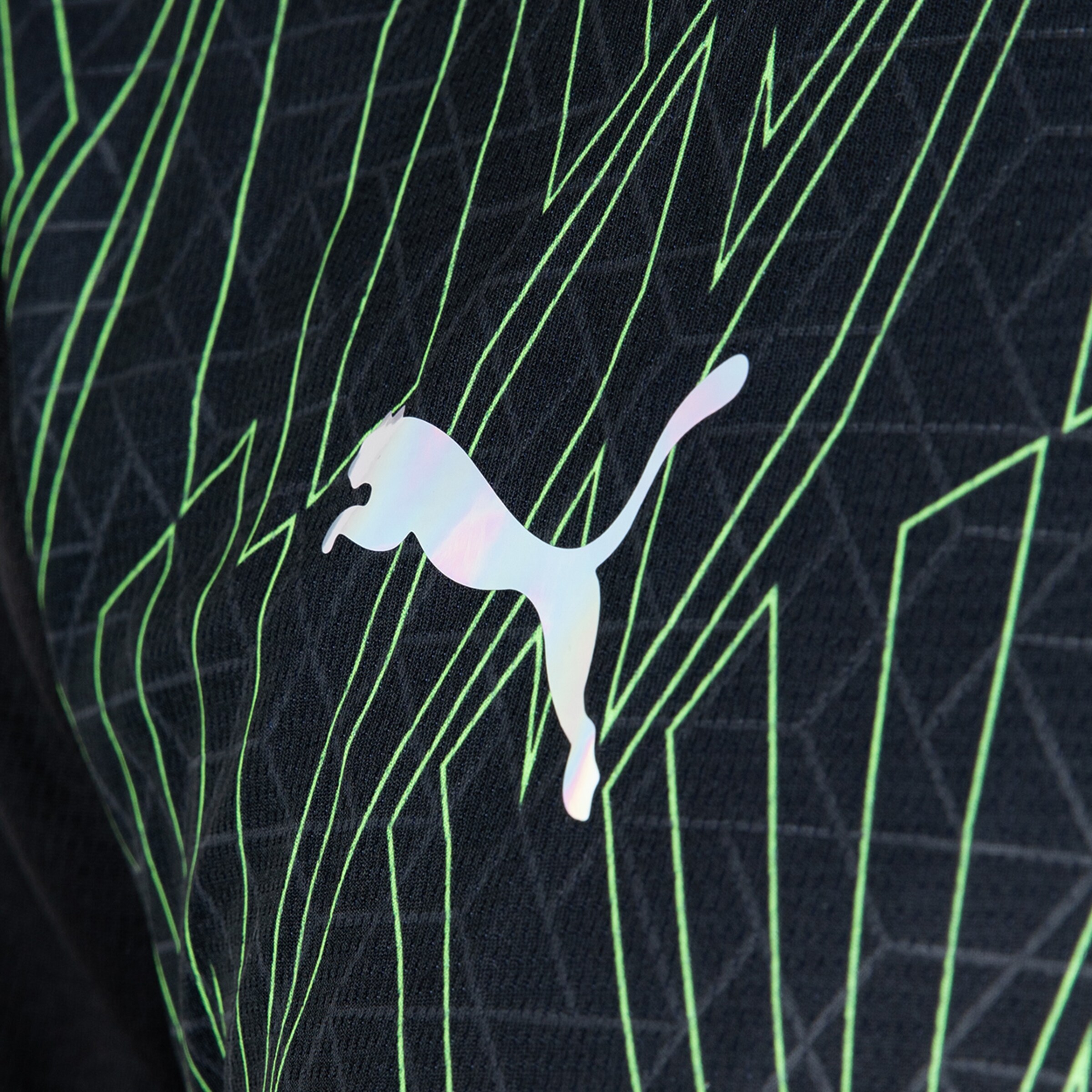 Puma logo on a black jersey with green geometric patterns.