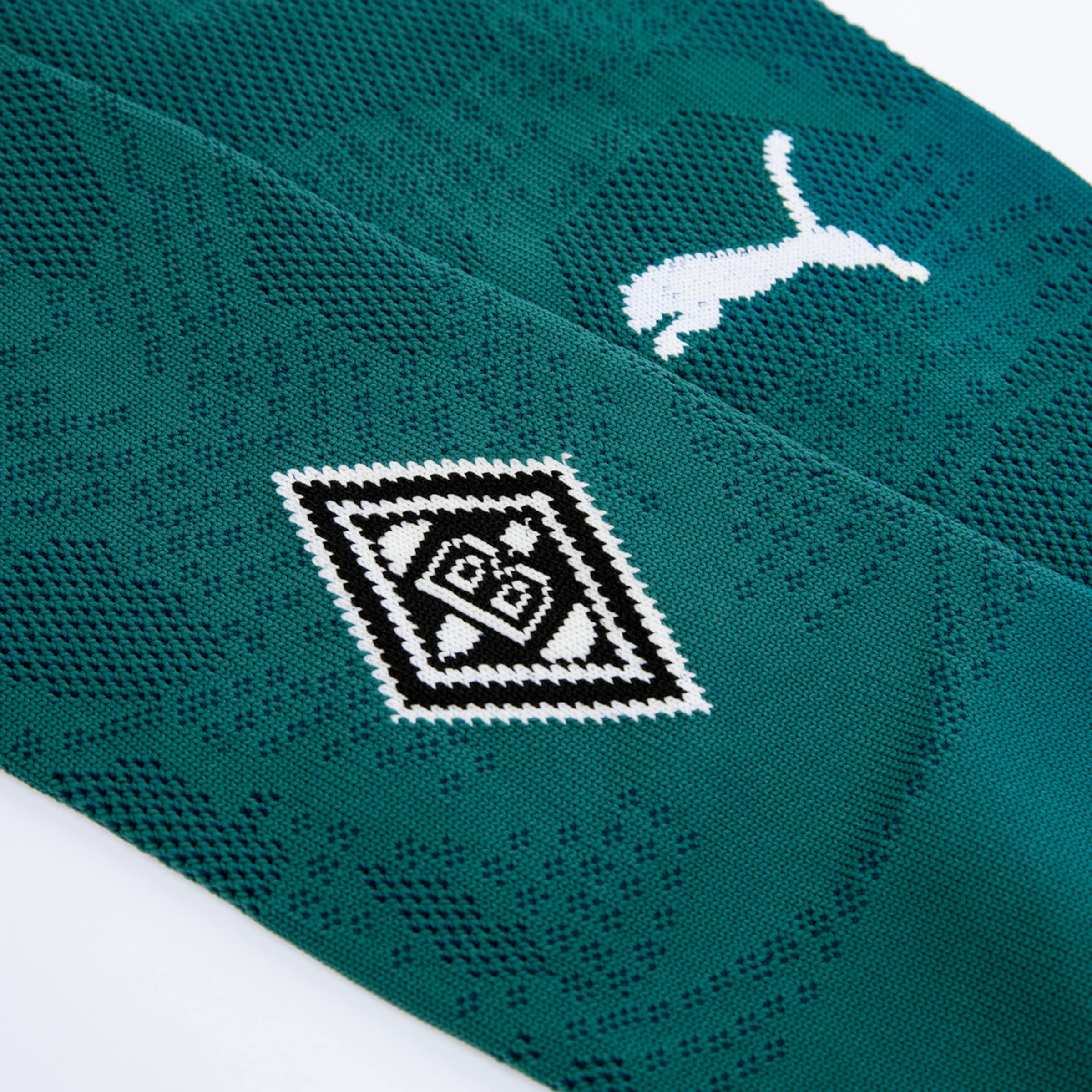 Detailansicht eines grünen Trikots mit Puma-Logo und Borussia Mönchengladbach-Emblem.