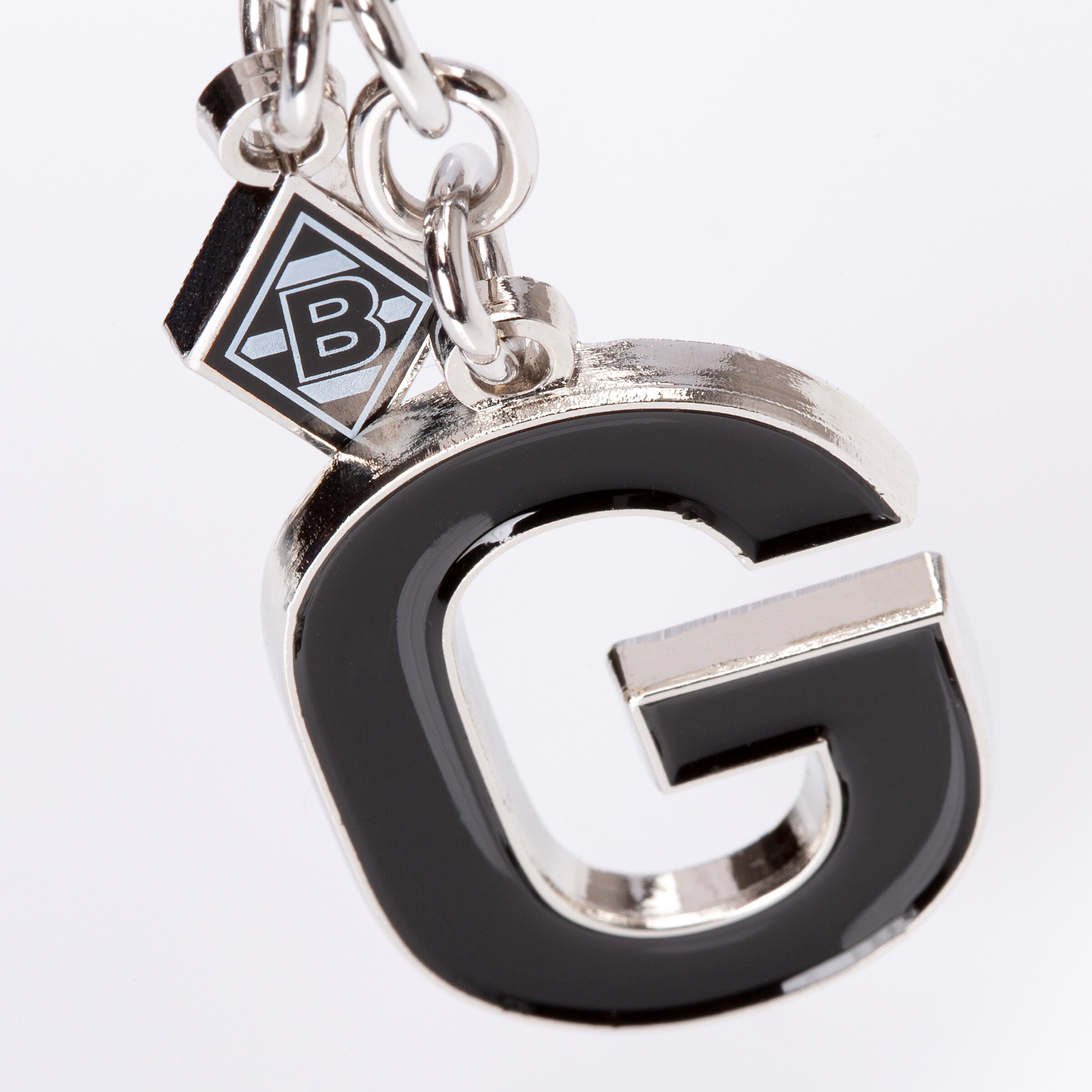 Schlüsselanhänger mit großem schwarzen Buchstaben G und kleinem Borussia Mönchengladbach Rauten-Logo an einer silbernen Gliederkette.