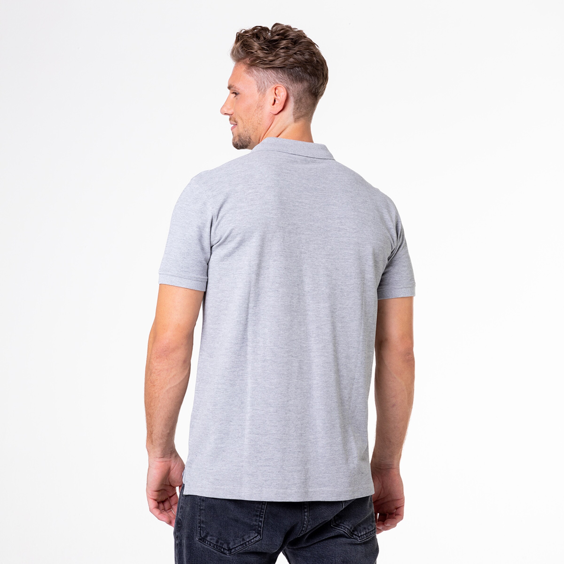 Mann trägt ein graues Poloshirt und schaut über die Schulter.