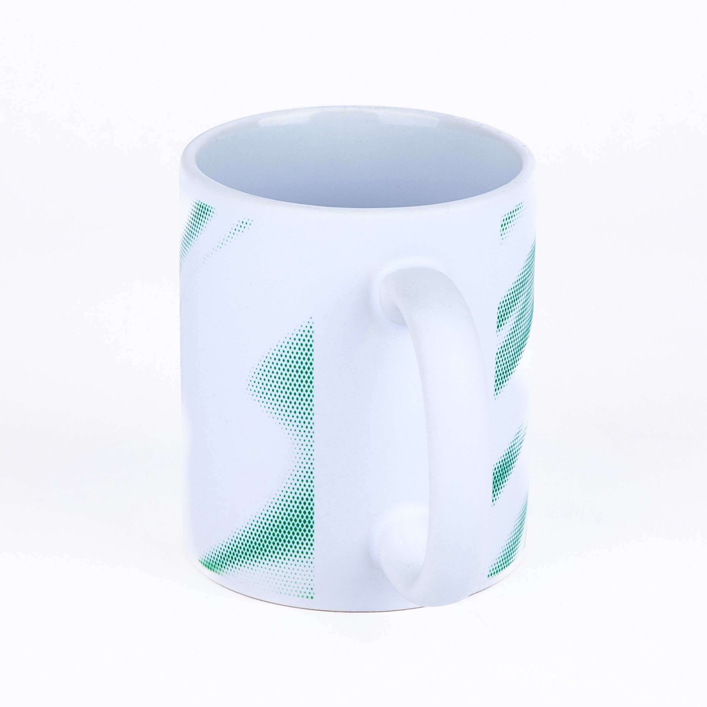 Weiße Keramiktasse mit abstrakten grünen Punktmustern auf weißem Hintergrund.