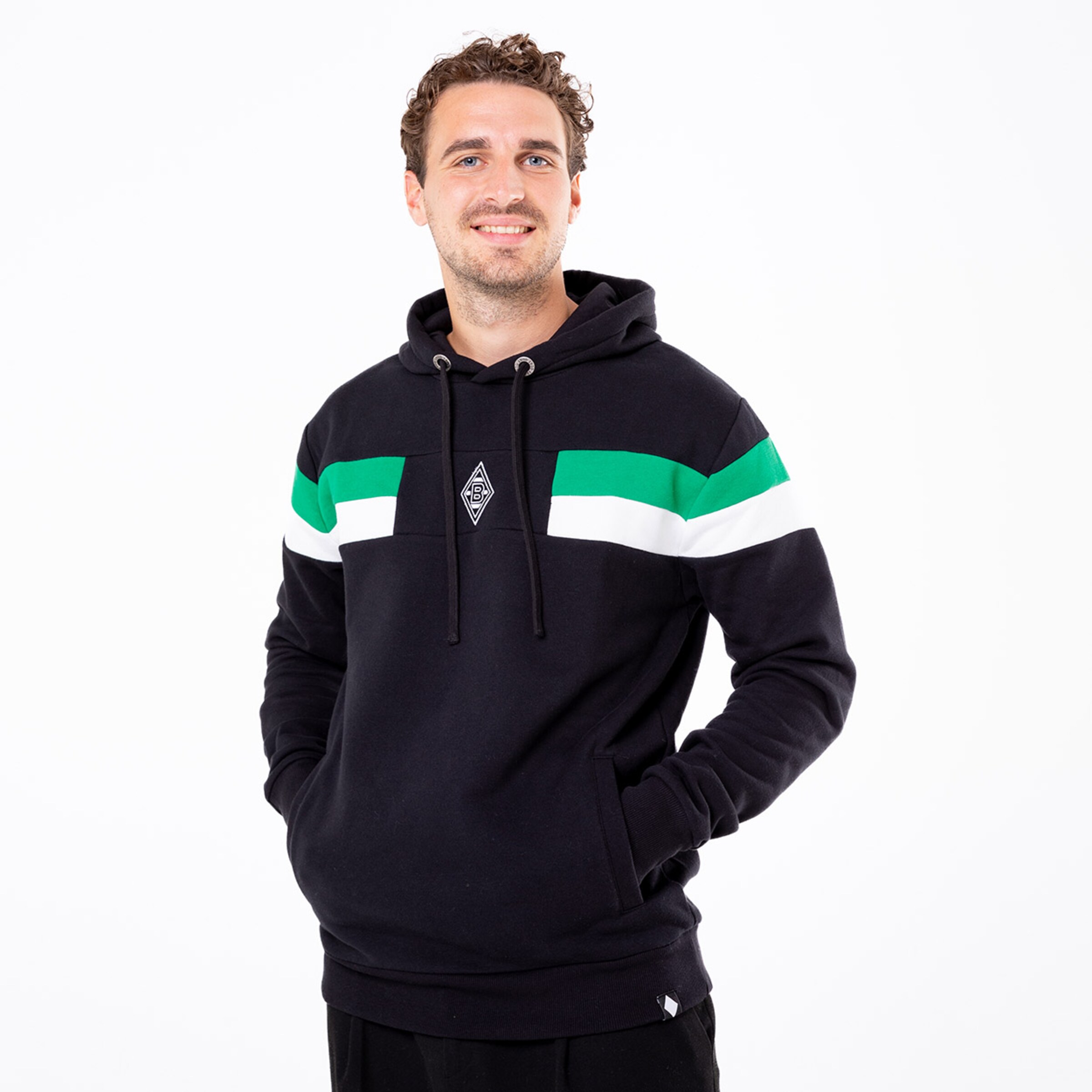 Mann in schwarzem Hoodie mit grünen und weißen Streifen lächelnd.