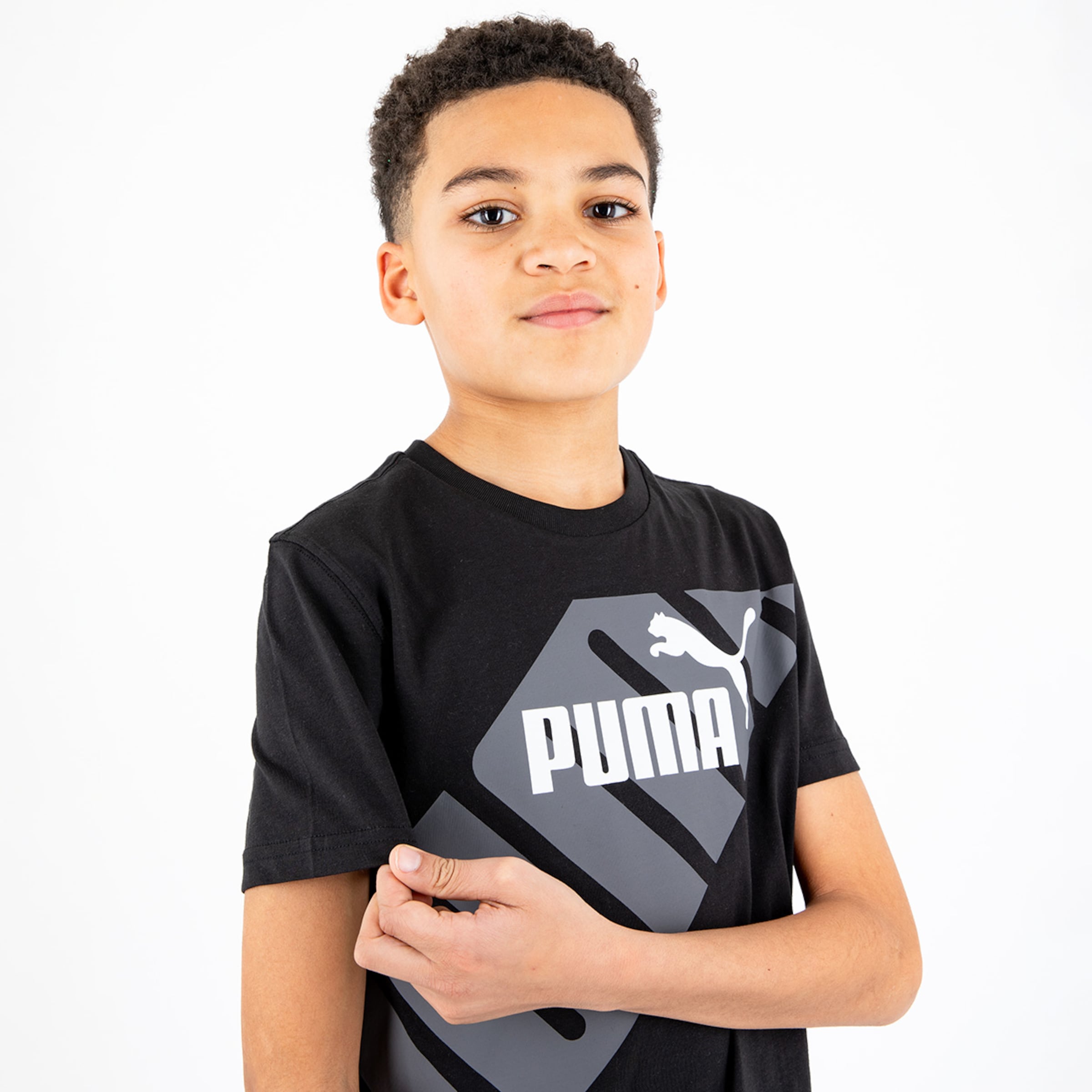 Boy wearing a black t-shirt featuring the Puma logo posing with a slight smile.