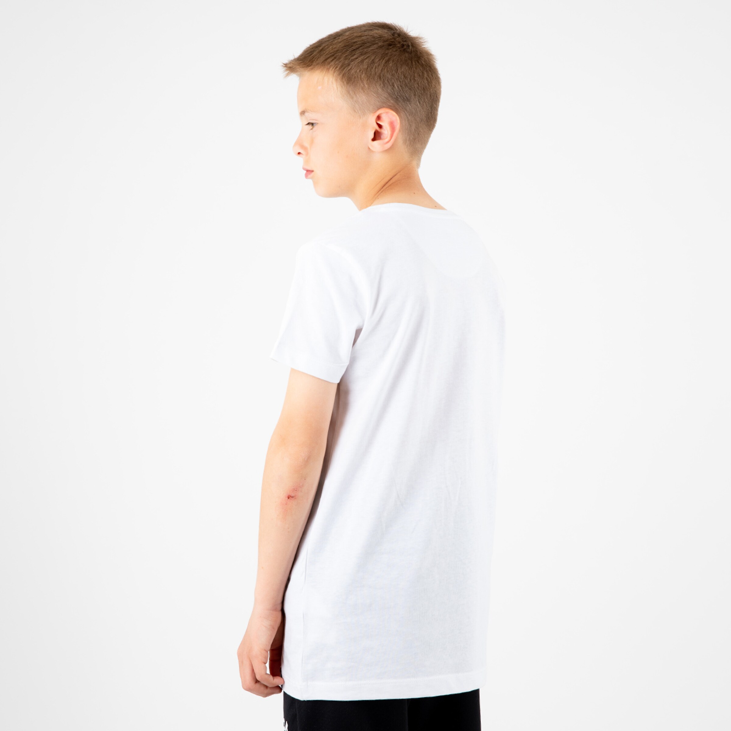 Junge mit kurzem weißen T-Shirt von der Seite gesehen.