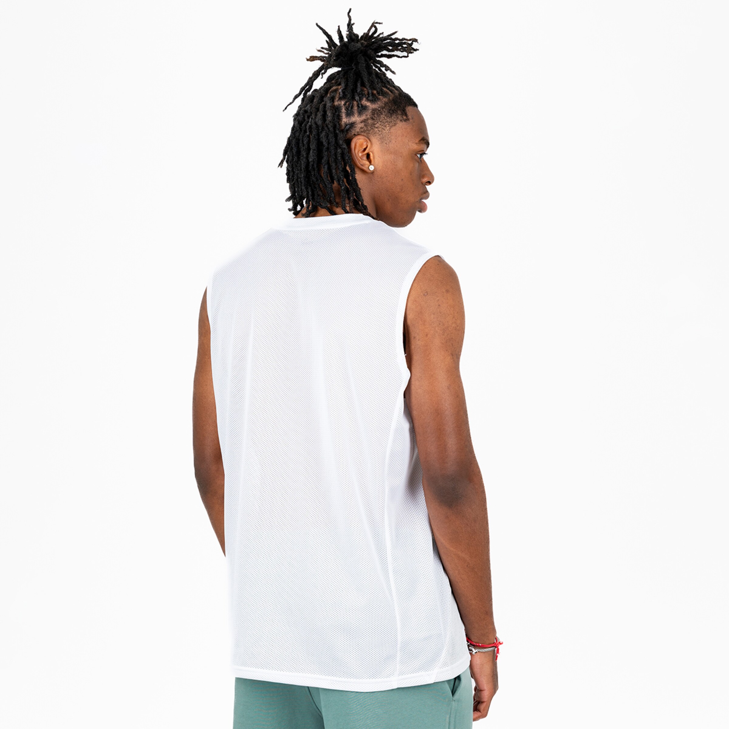 A young man with dreadlocks is wearing a sleeveless white athletic shirt and looking over his shoulder.