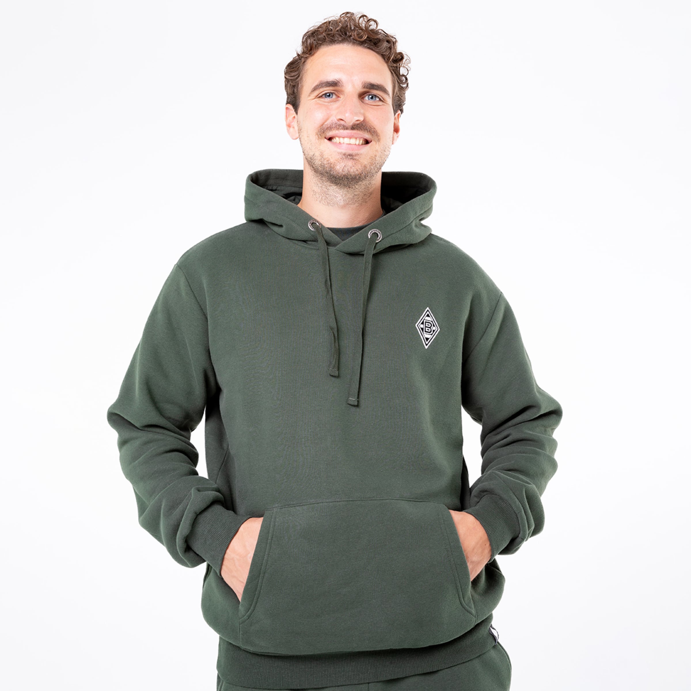 Mann lächelt in einem grünen Hoodie mit aufgenähtem Borussia Mönchengladbach-Logo.