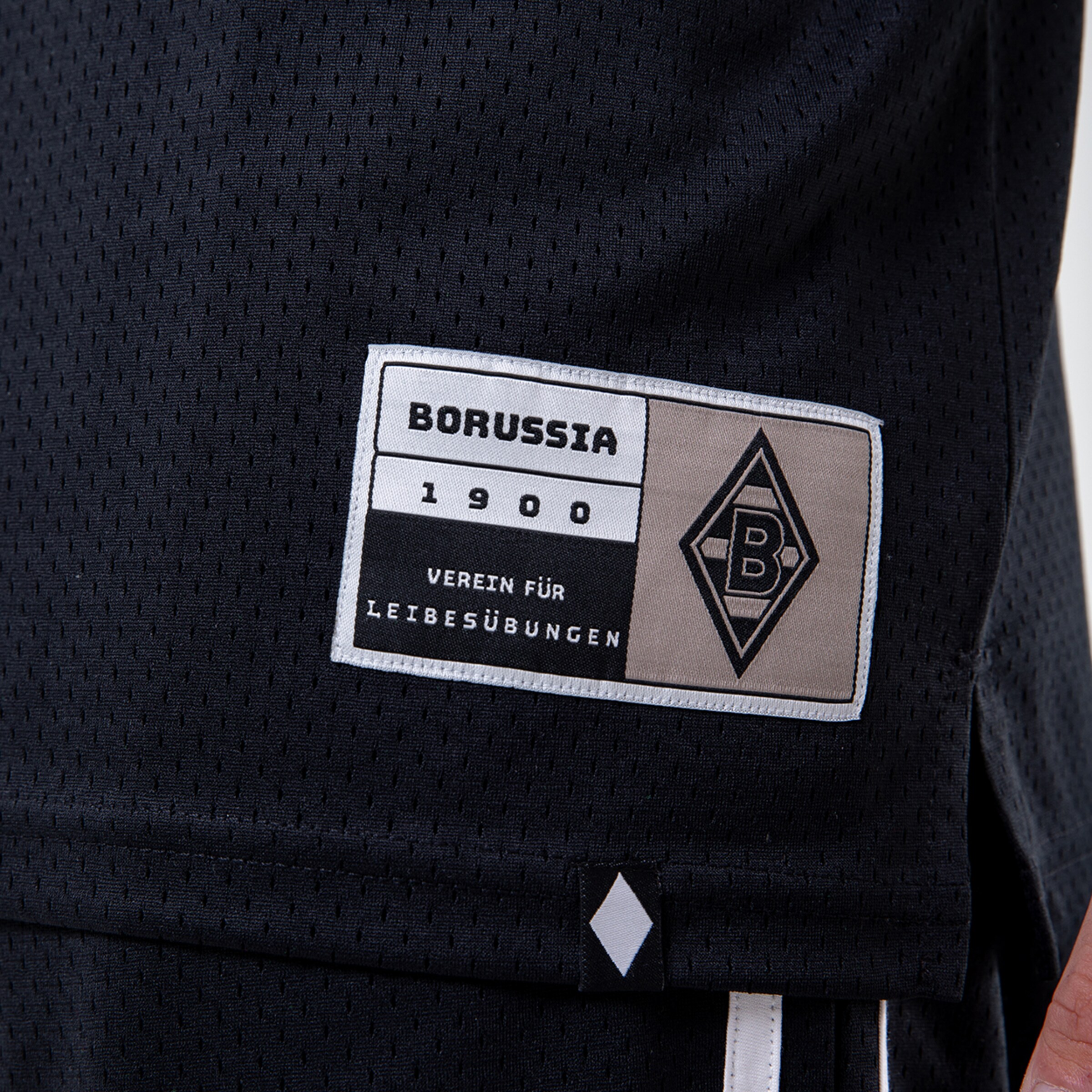 Detailaufnahme des Borussia Mönchengladbach Trikots mit einem Etikett das das Gründungsjahr 1900 zeigt.