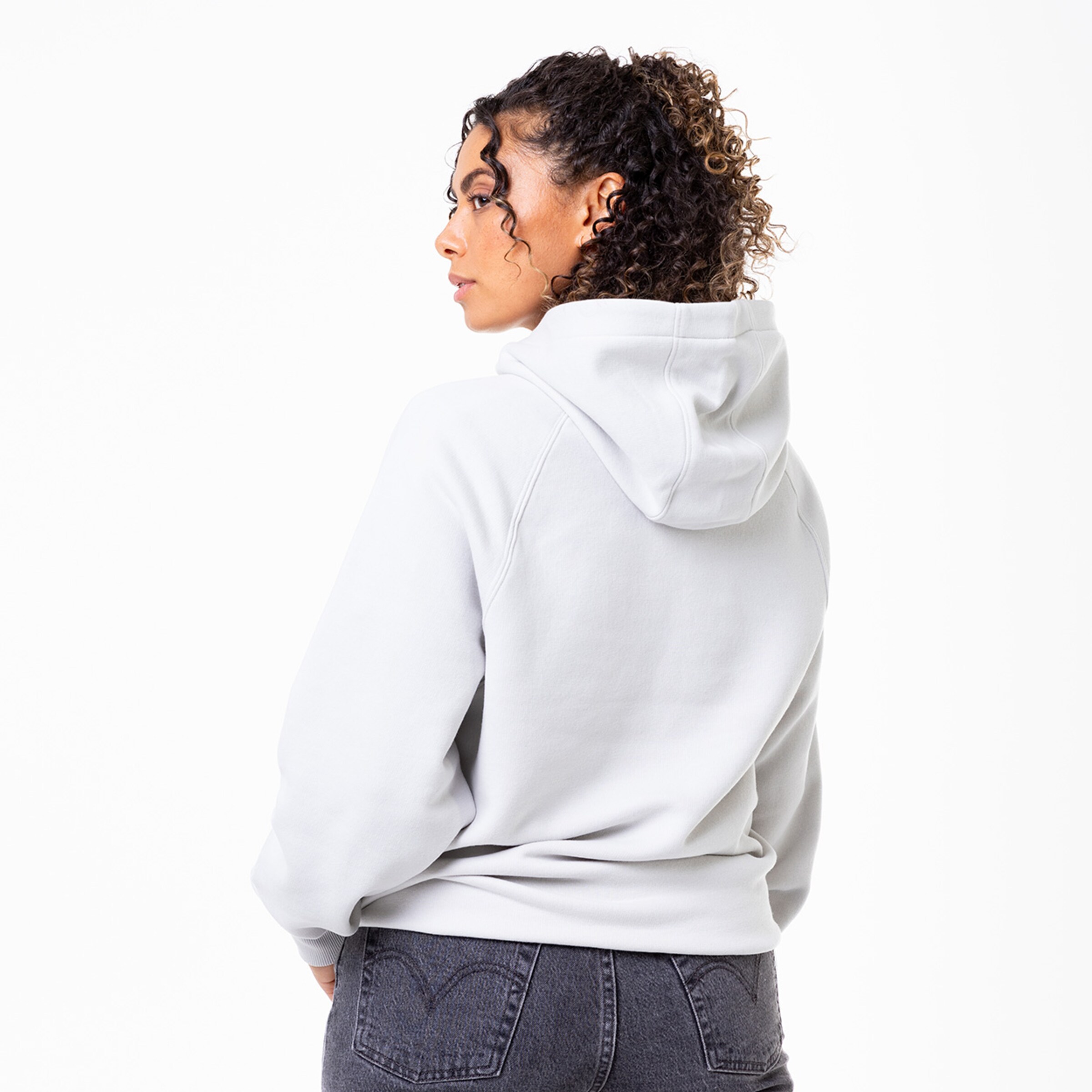 Frau in grauem Hoodie von hinten mit lockigem Haar und Kapuze.