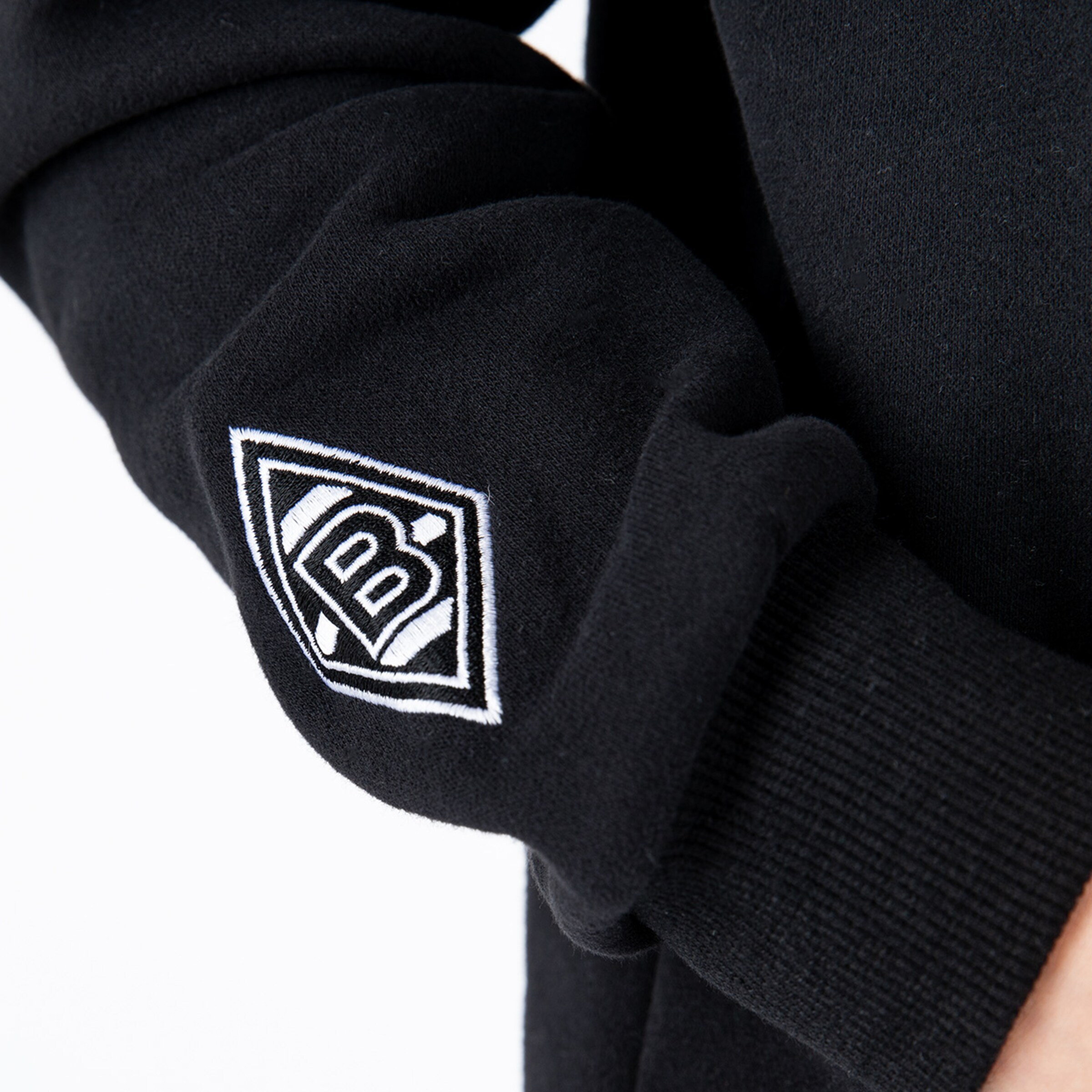Black sweatshirt sleeve with embroidered Borussia Mönchengladbach logo.