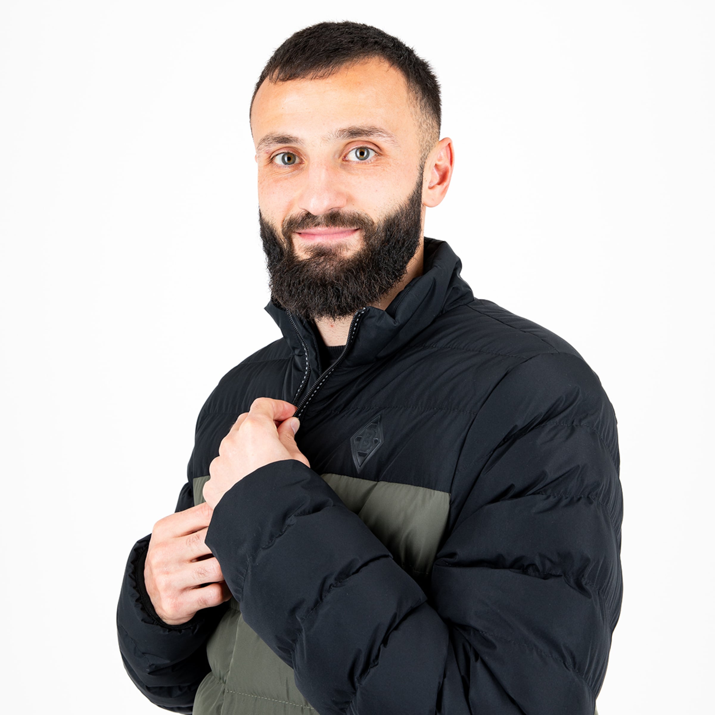 Mann mit Bart in schwarzer Jacke hält den Reißverschluss fest