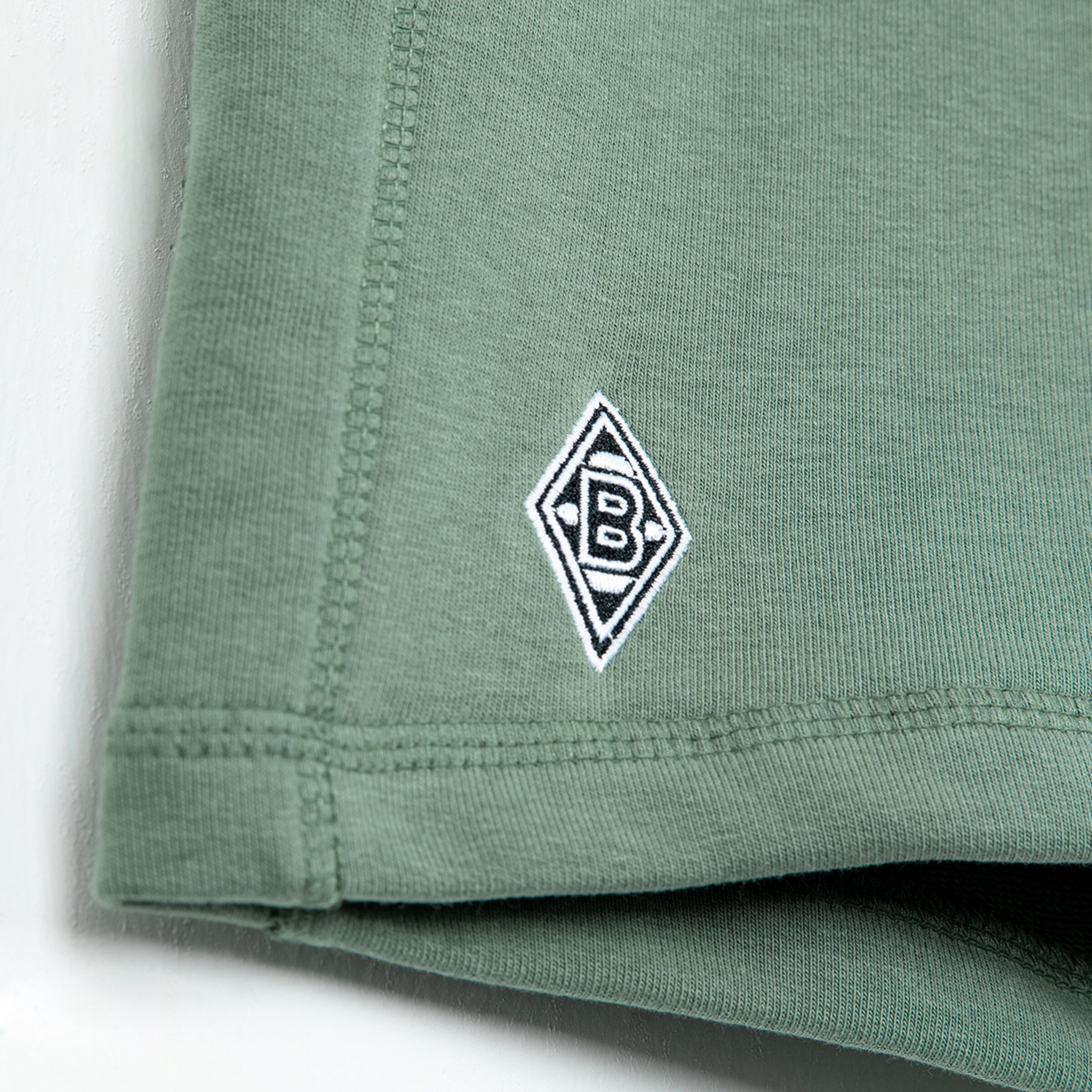 Nahaufnahme des Borussia Mönchengladbach Logos auf einem grünen Shirt.