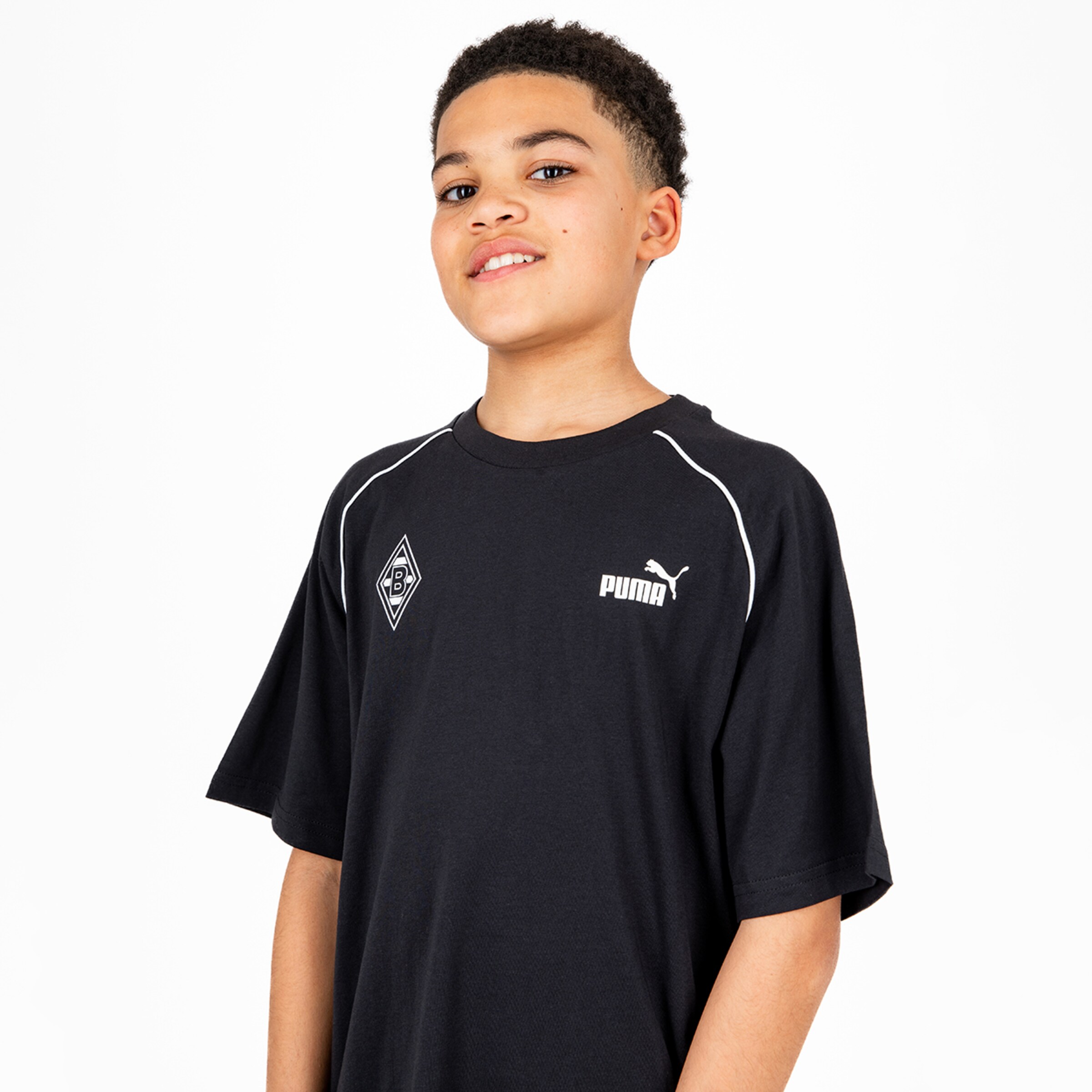 Junger Junge in schwarzem T-Shirt mit Puma-Logo und Borussia Mönchengladbach-Wappen.