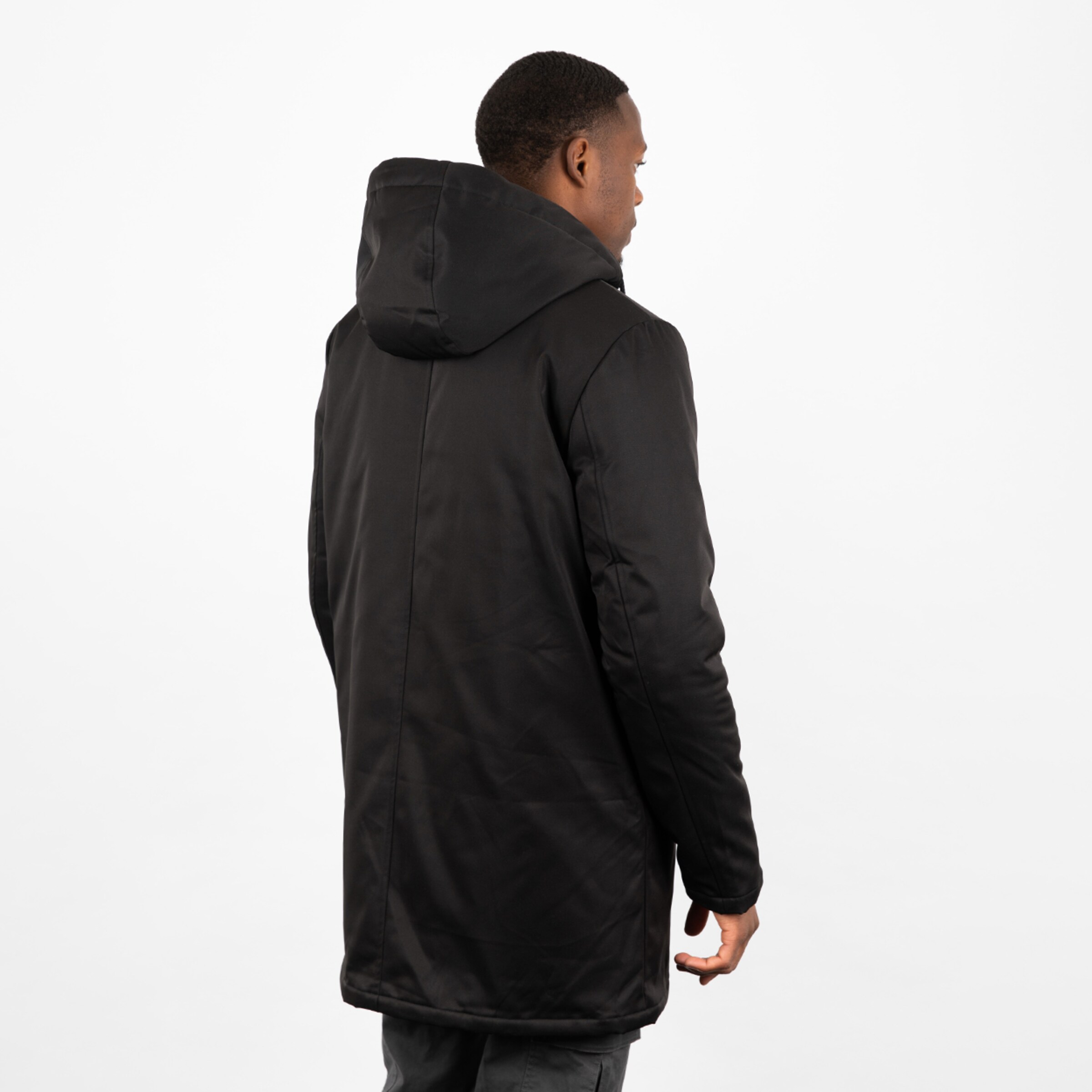 Mann steht mit dem Rücken zur Kamera in einer schwarzen Jacke.