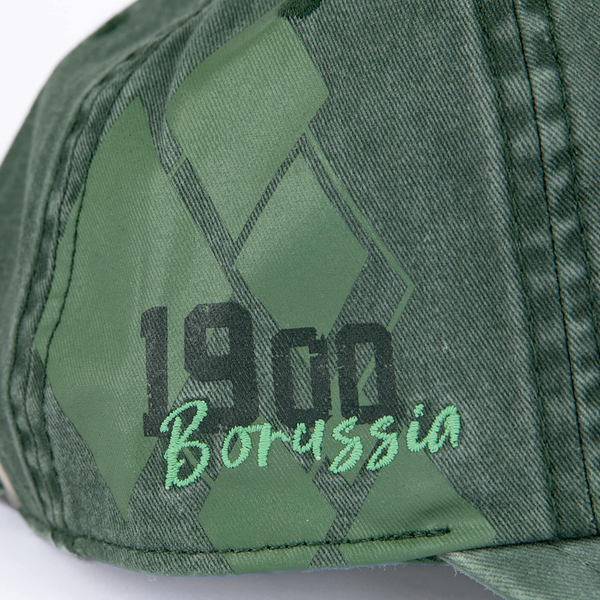 Nahaufnahme einer grünen Cap mit Rautenmuster, schwarzer Zahl „1900“ und hellgrünem Stickerei-Schriftzug „Borussia“.
