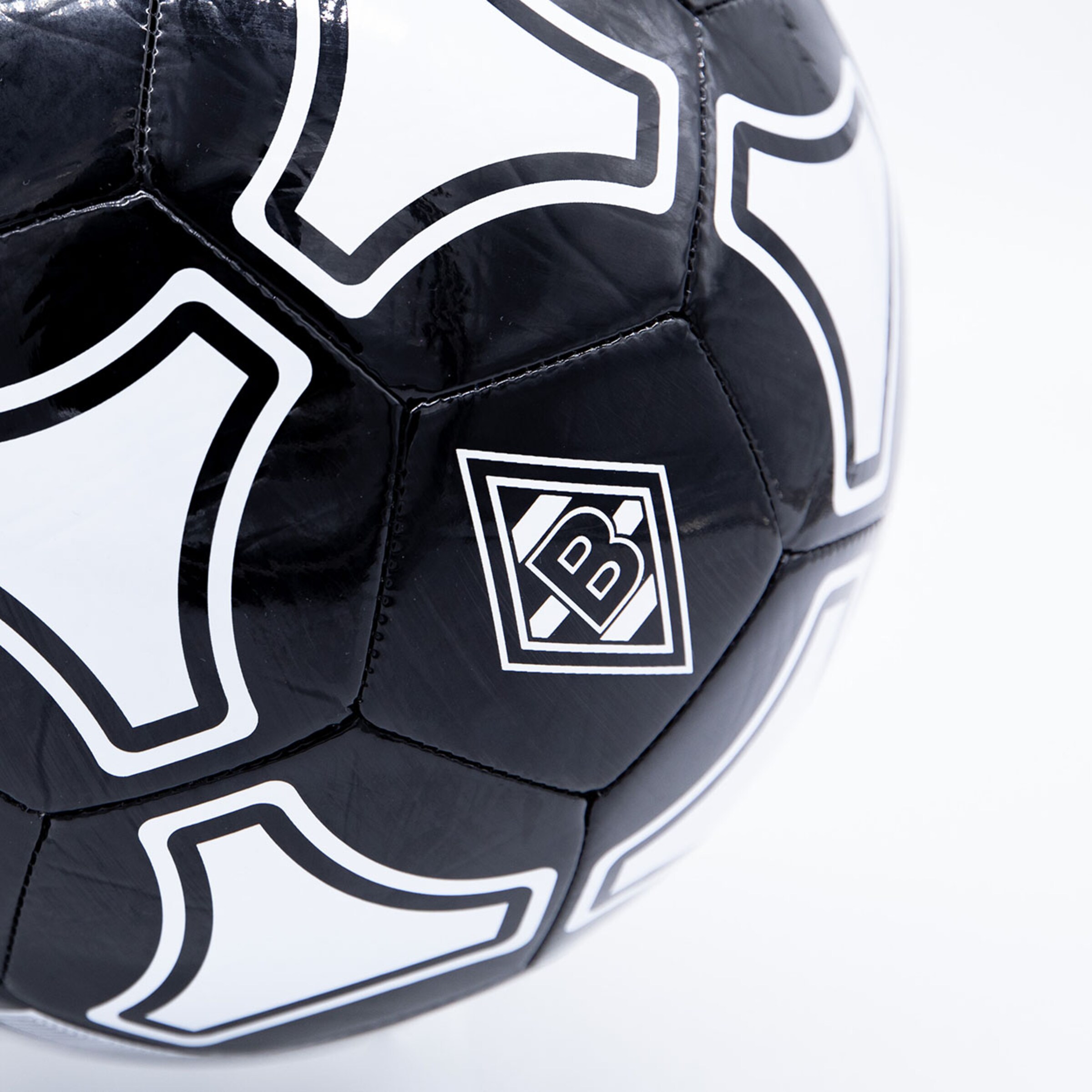 Nahaufnahme eines schwarz-weißen Fußballs mit glänzendem Finish, Tango-Design-Mustern und einem quadratischen Logo mit dem Buchstaben B.
