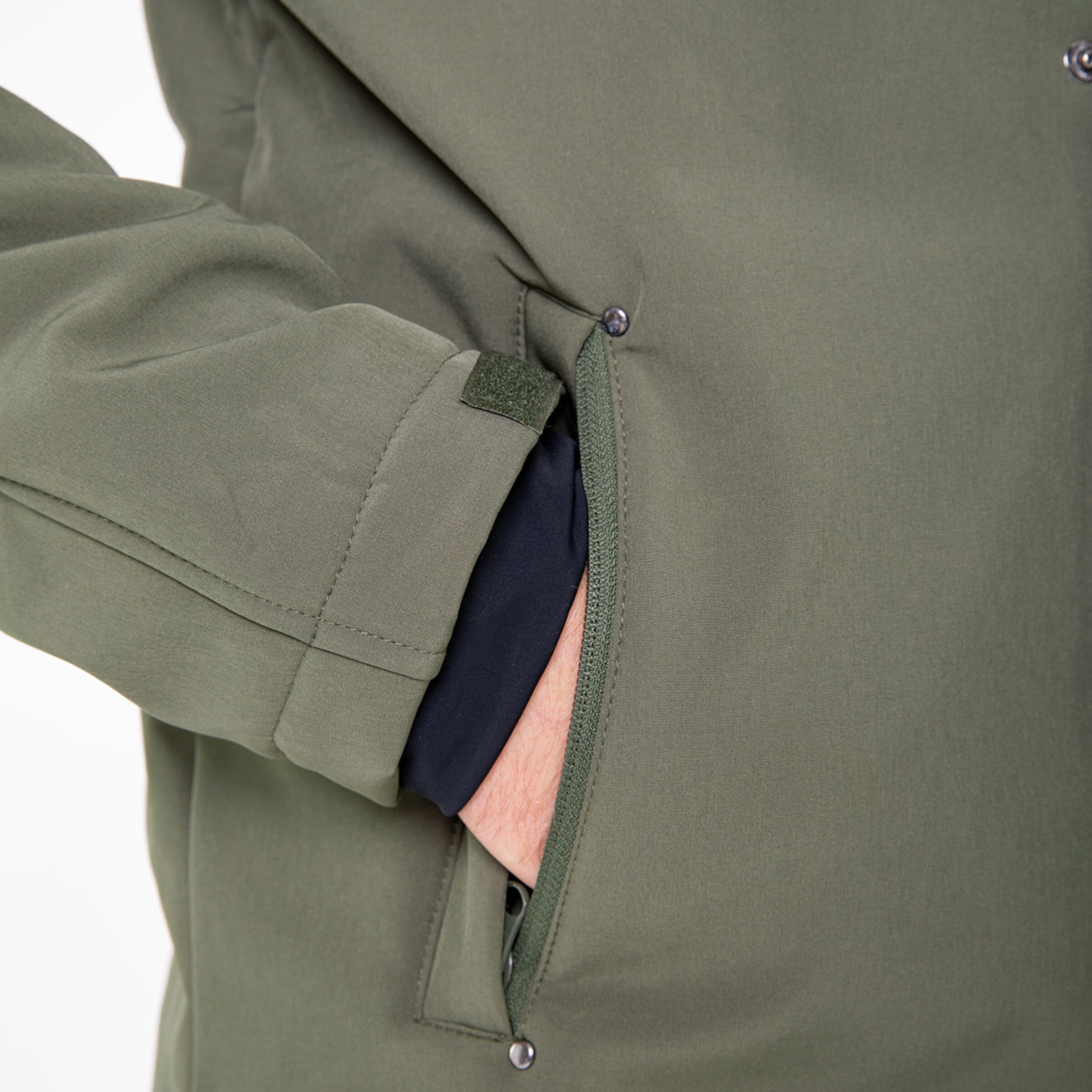 Nahaufnahme einer Person mit einer Jacke in Olivgrün die ihre Hand in der Tasche hat.