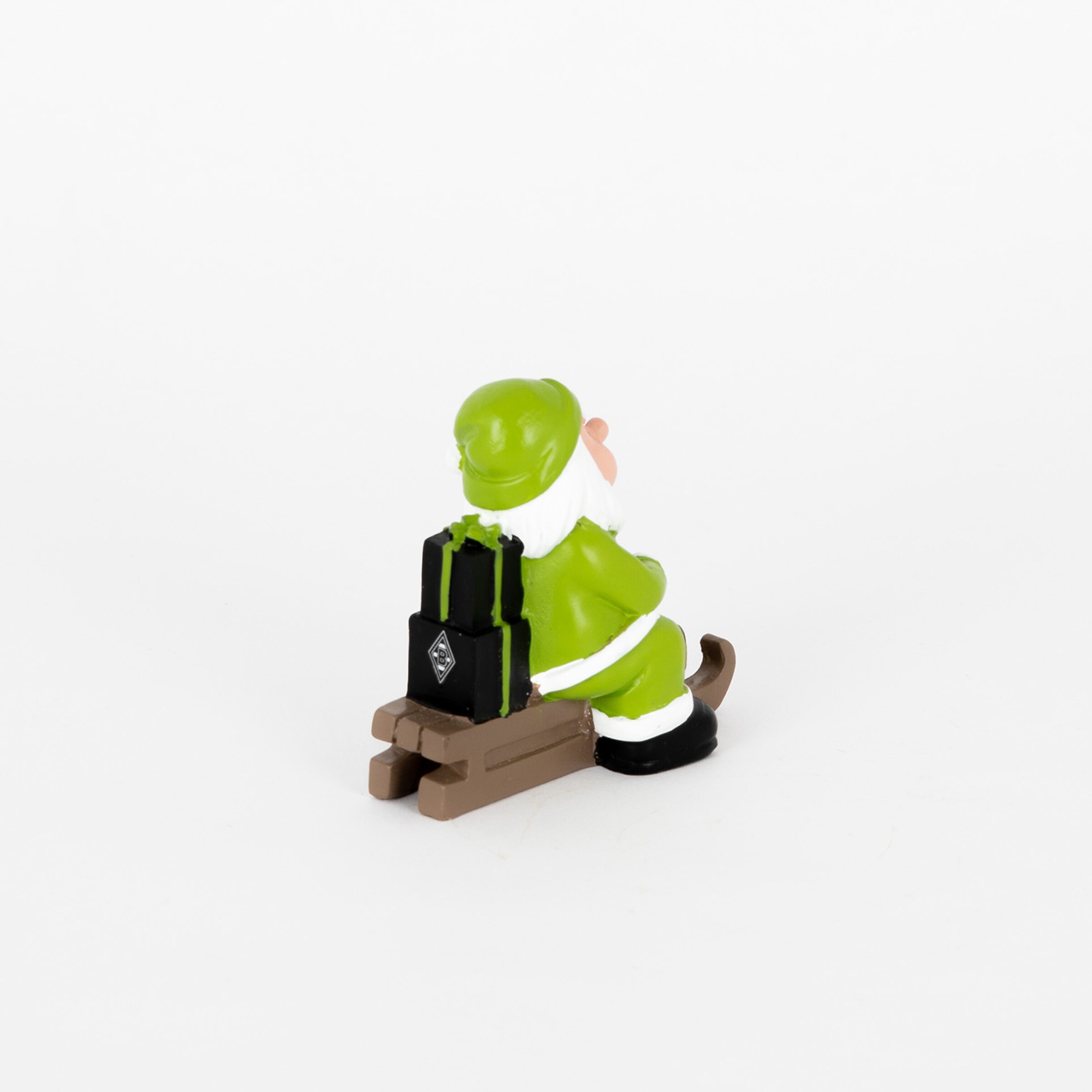 Eine grüne Figur auf einem Schlitten der mit Koffern beladen ist.