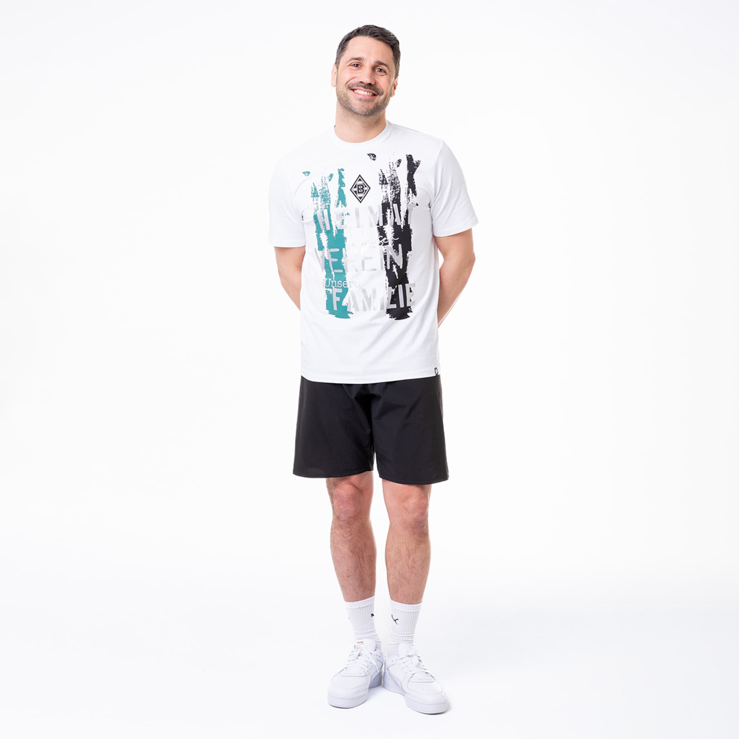 Mann trägt ein oberteil mit grafischem Druck und schwarze Shorts.