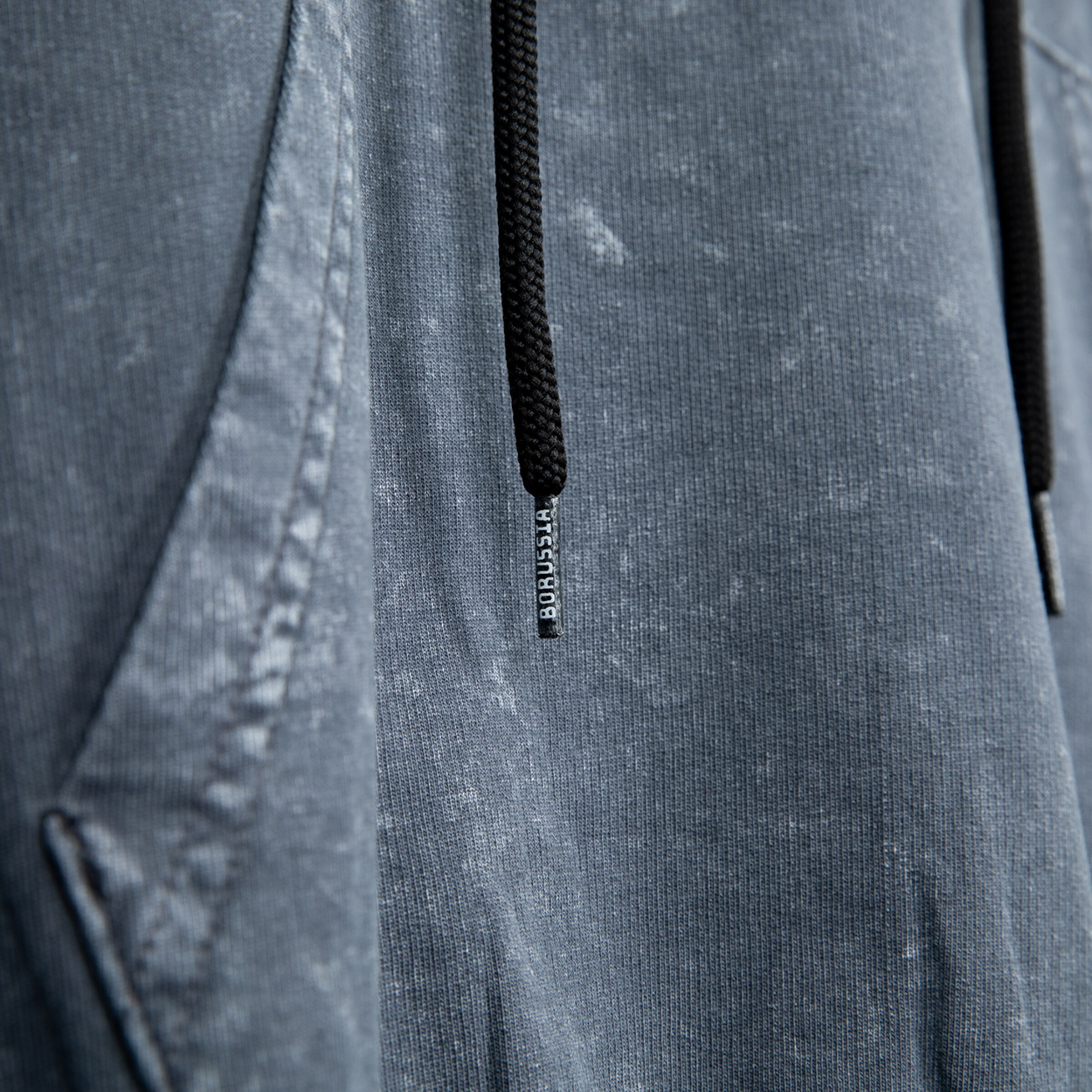 Detailaufnahme eines grauen Sweatshirts mit Kordelzug.