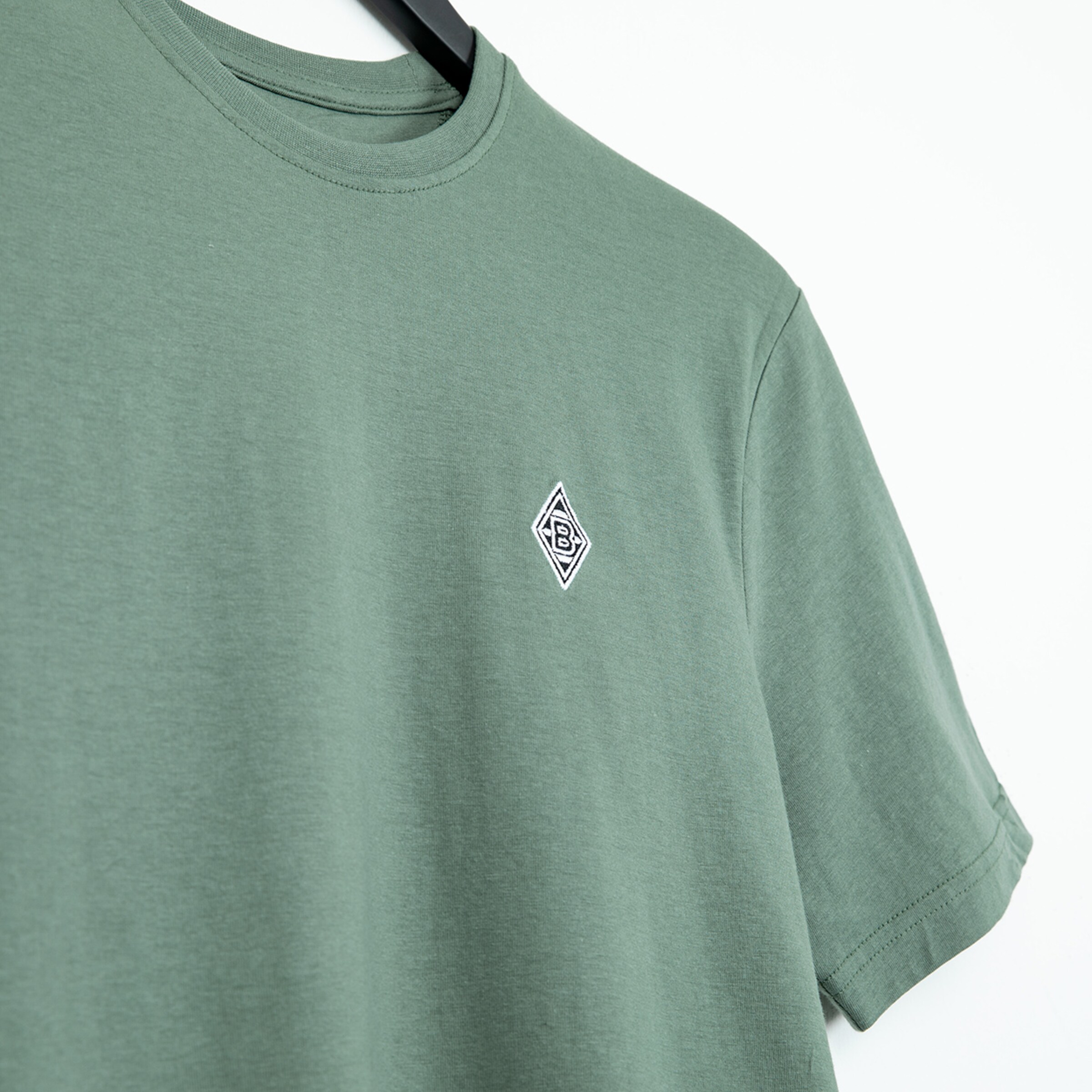 Grüne T-Shirt mit kleinem Borussia Mönchengladbach Logo auf der Brust.