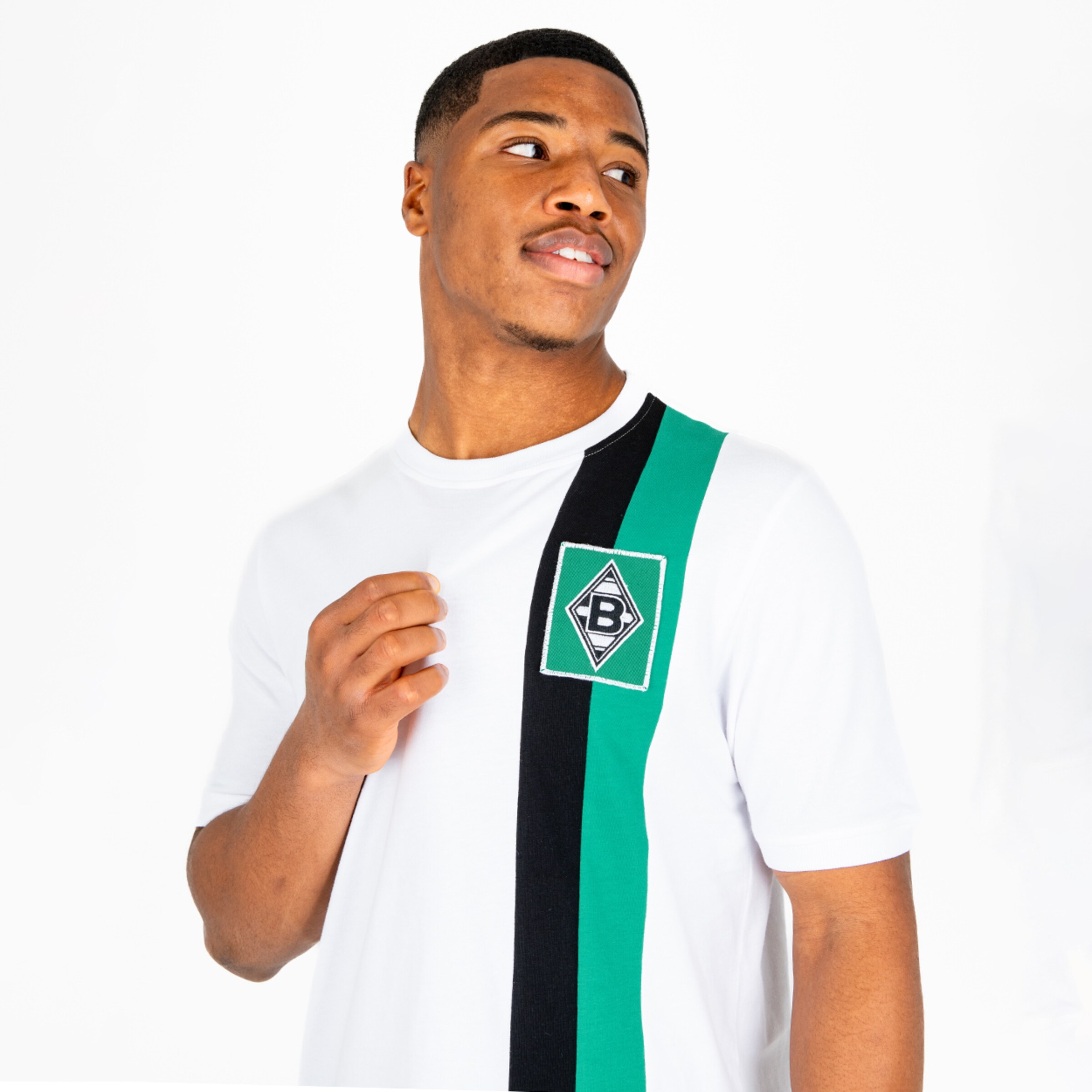 Ein junger Mann trägt ein schlichtes T-Shirt mit dem Borussia Mönchengladbach-Logo in der Mitte.